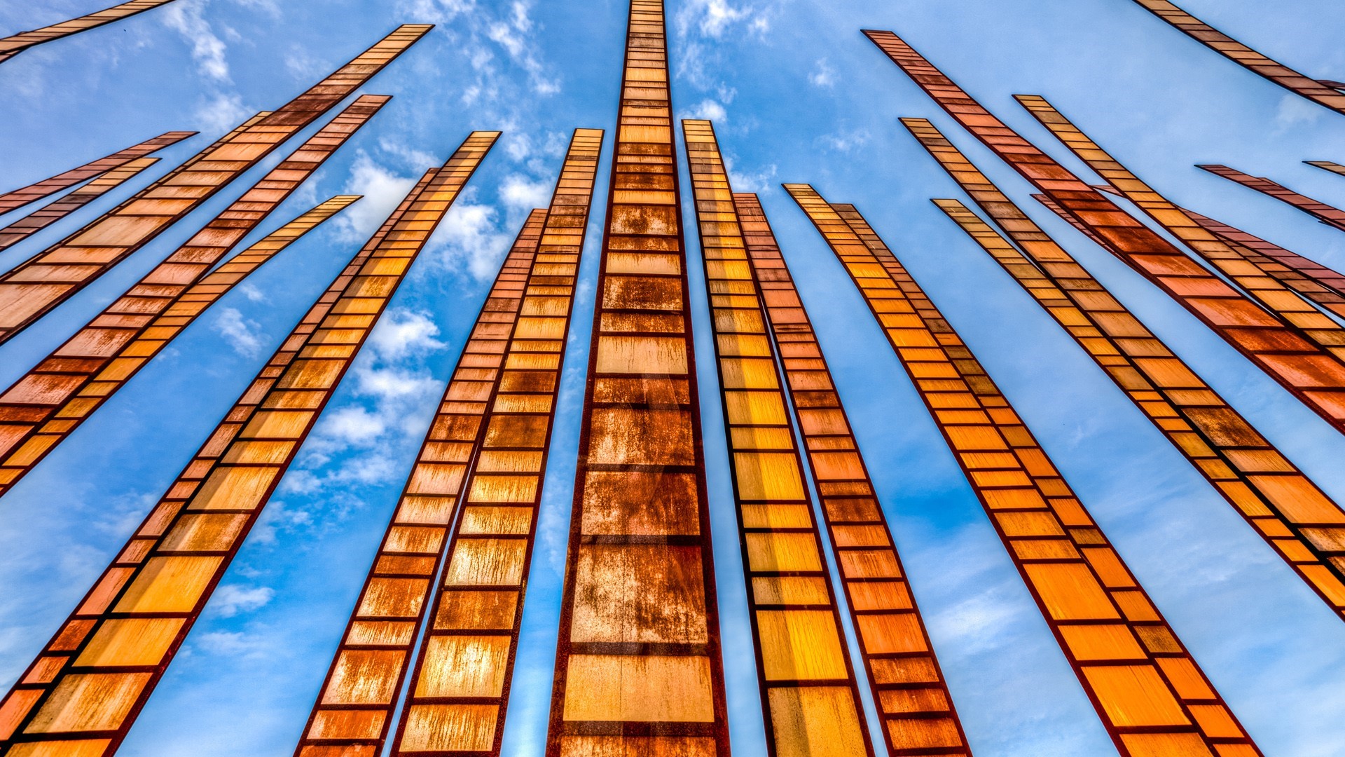 Orange sculptures against a blue sky with clouds HD Wallpaper