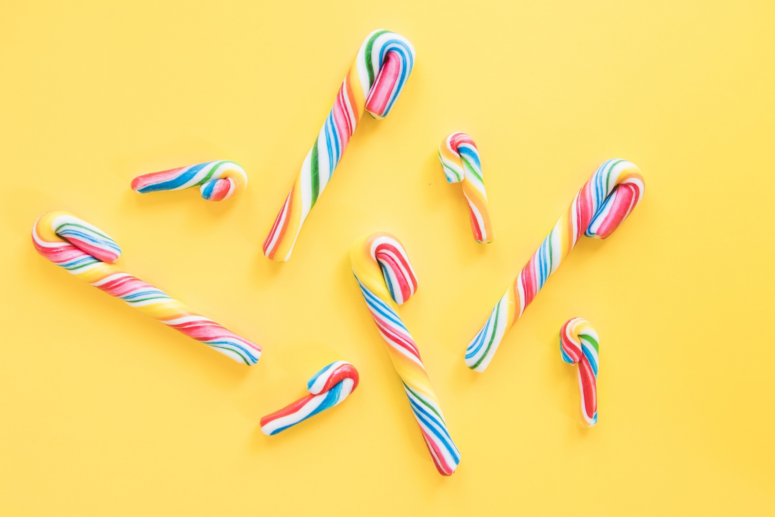 Colorful candy canes on a yellow background HD Wallpaper