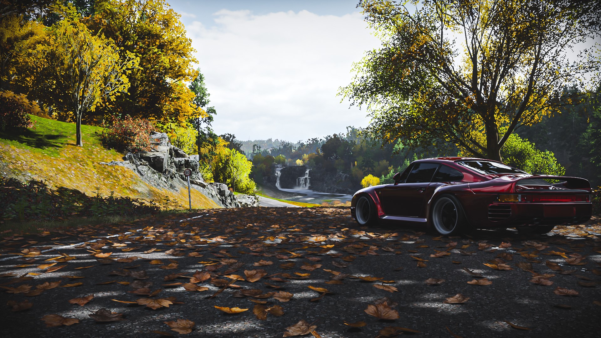 Red Porsche 959 on a road with autumn leaves HD Wallpaper