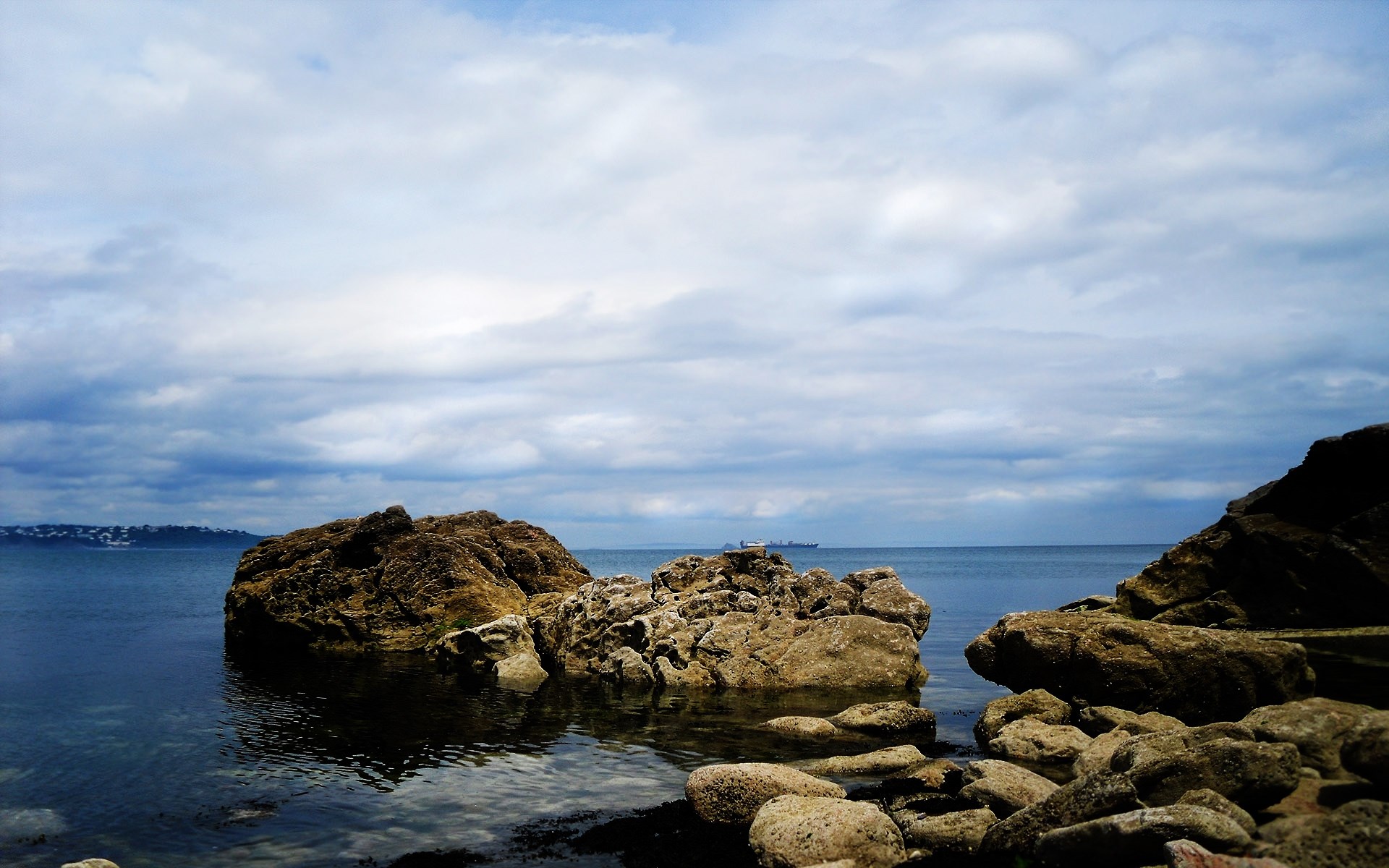 Rocky coastline with a ship on the horizon HD Wallpaper