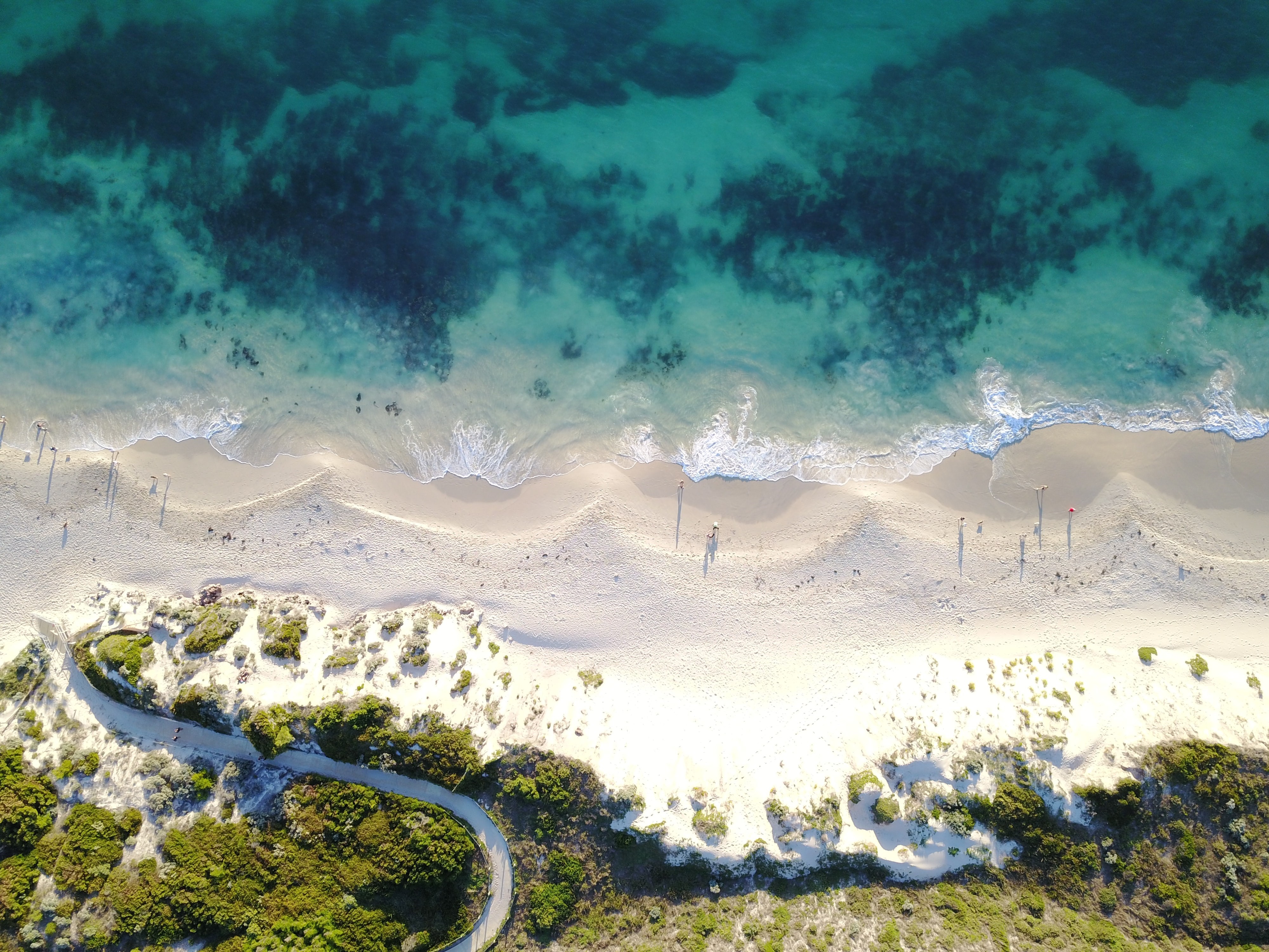 Aerial view of a sandy beach with turquoise water and vegetation HD Wallpaper