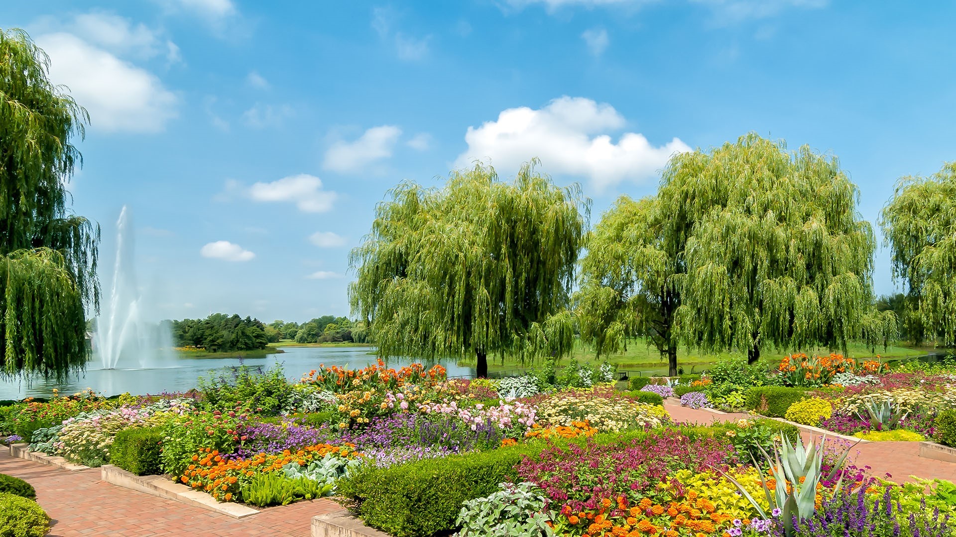 Botanical garden with lake, fountain, and colorful flowers HD Wallpaper