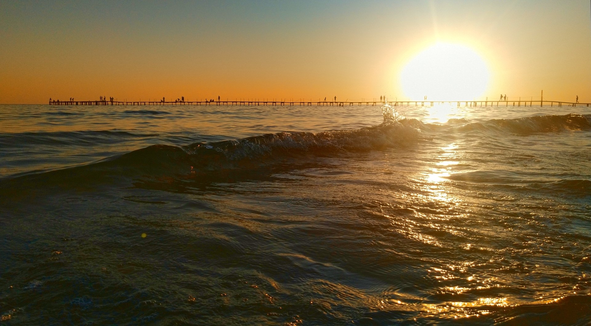 Sunset over the sea with a pier and people HD Wallpaper