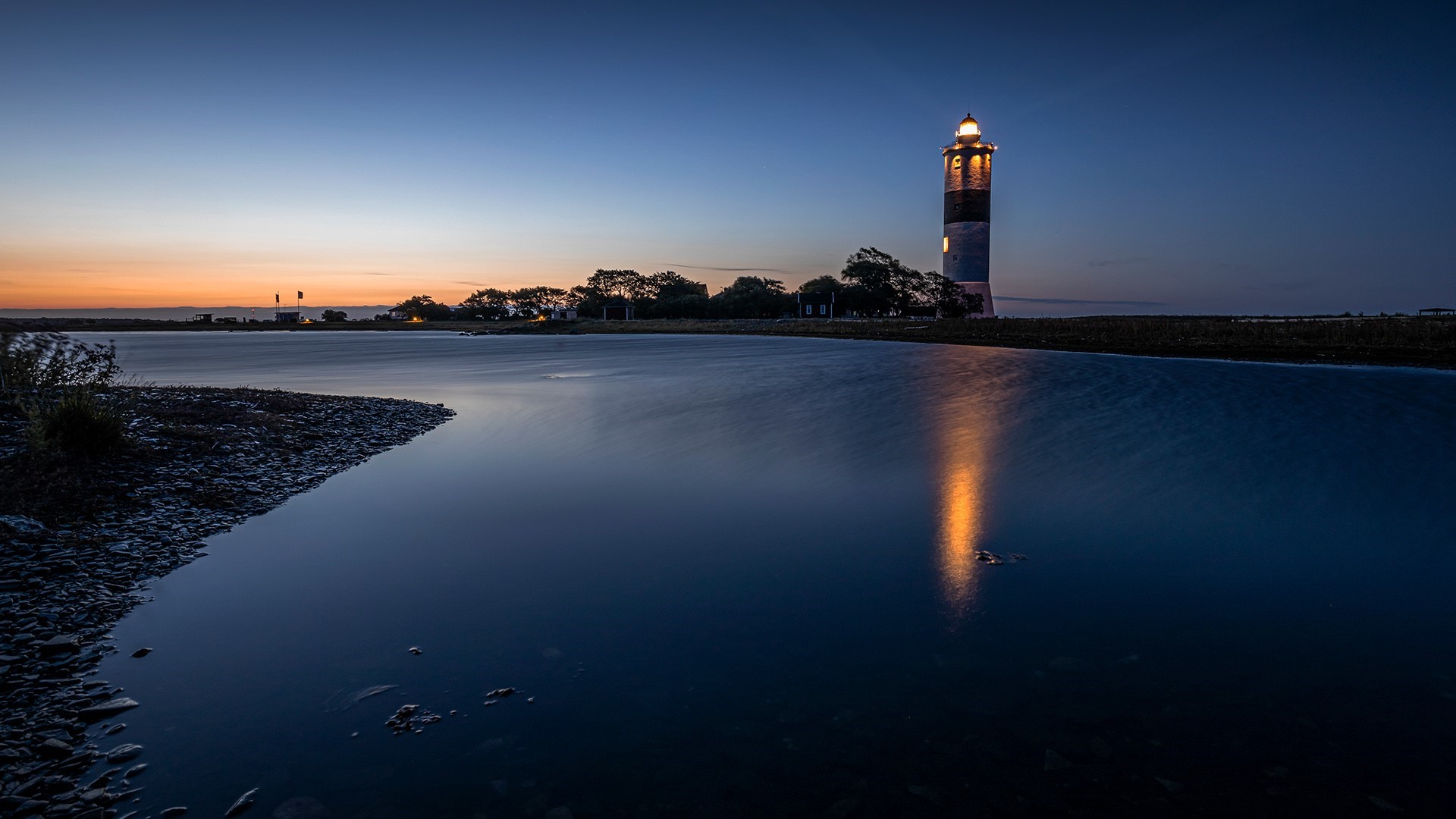 Lighthouse at dusk with reflection in water HD Wallpaper
