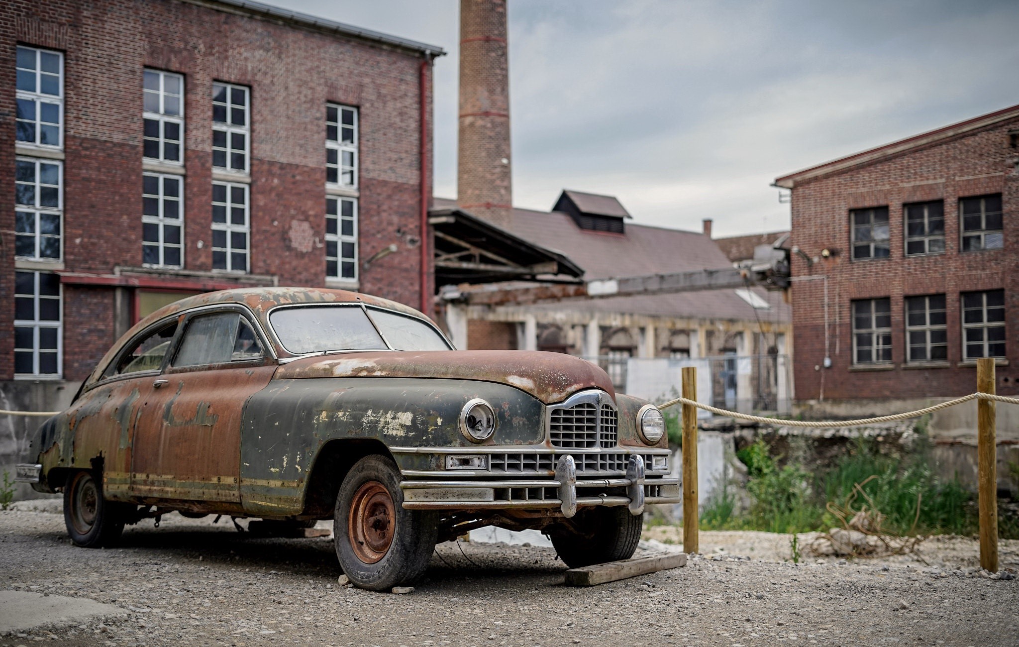 Rusted vintage car in front of abandoned brick factory HD Wallpaper