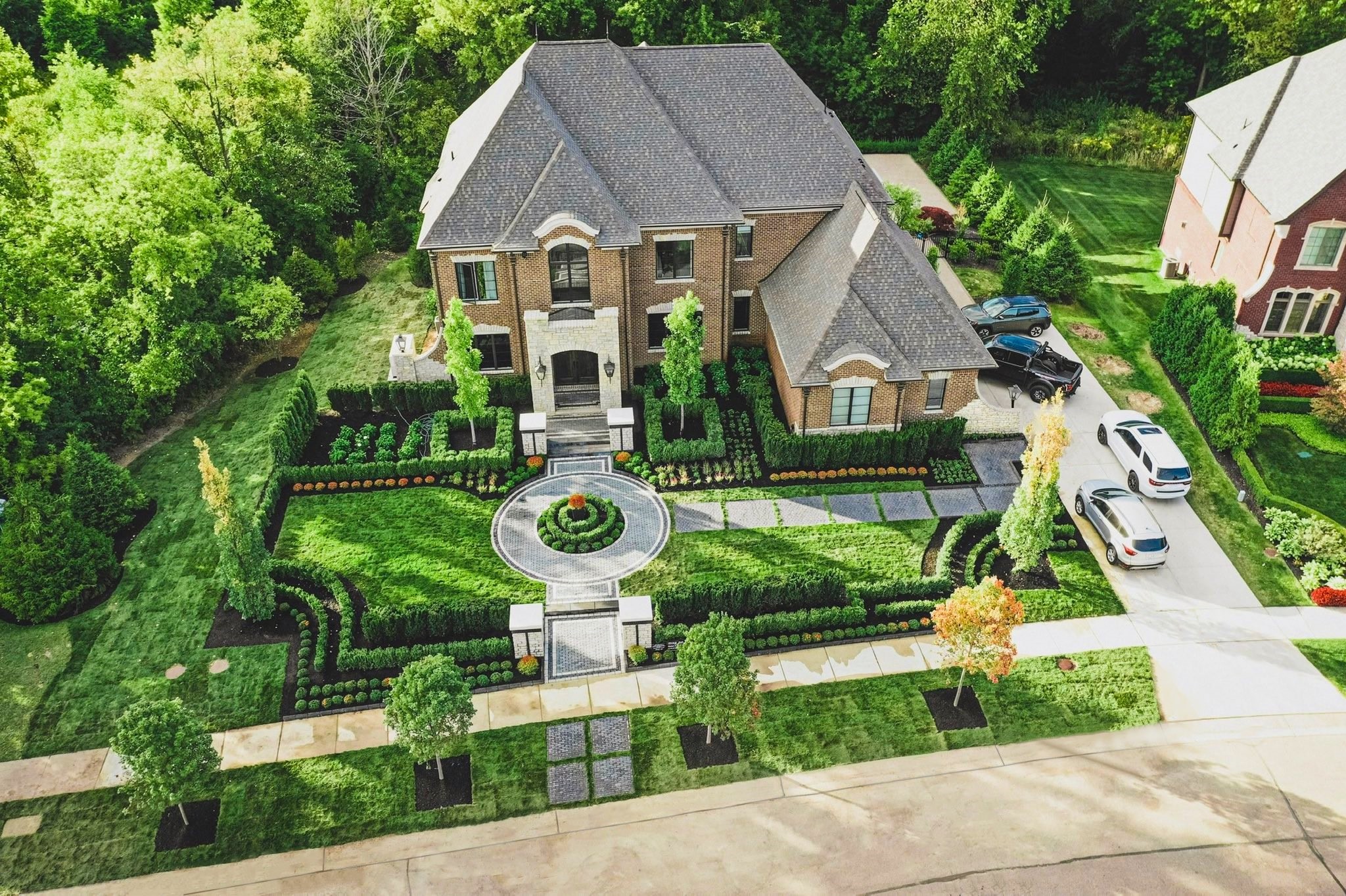 Luxury brick house with manicured gardens and cars HD Wallpaper