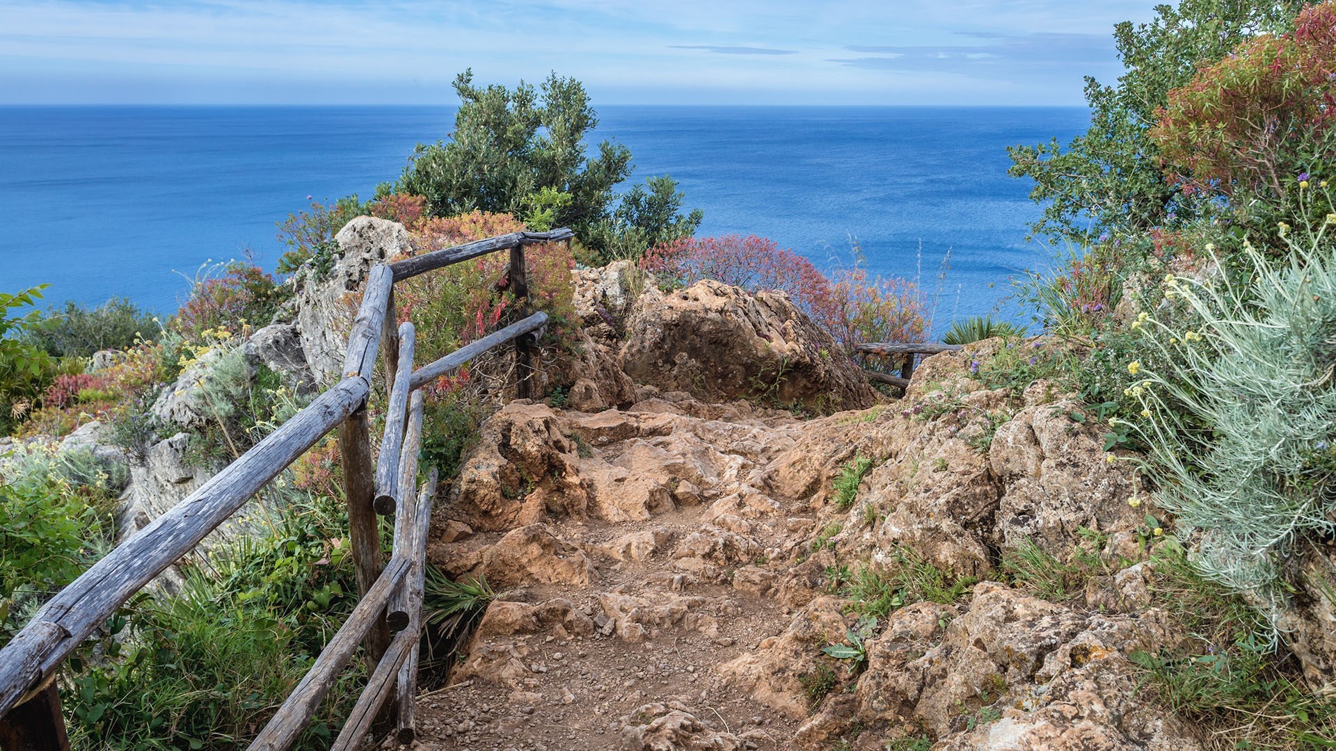 Rocky path with wooden railing overlooking the sea in Sicily HD Wallpaper