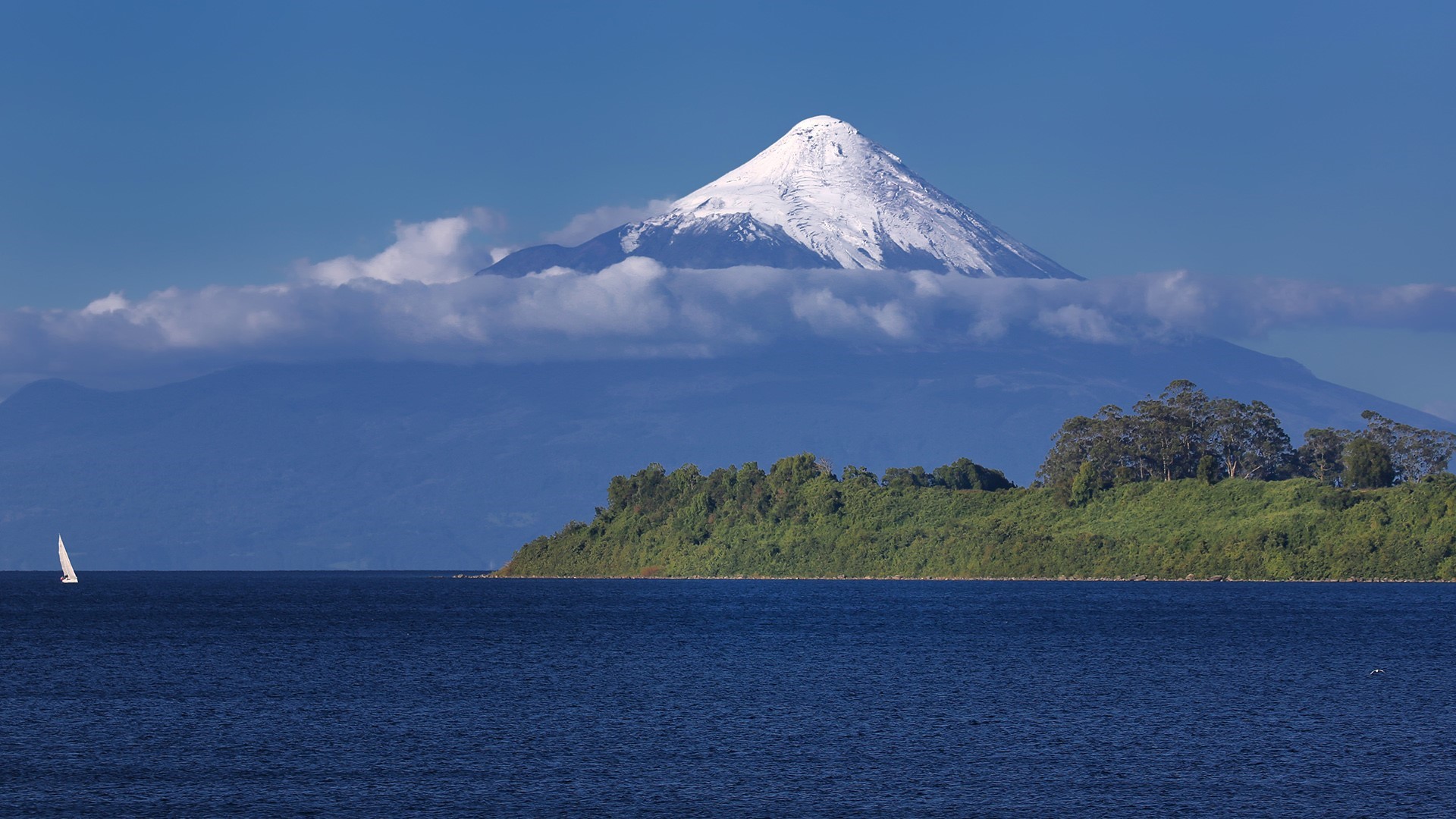 Snowy volcano over a lake with a sailboat HD Wallpaper