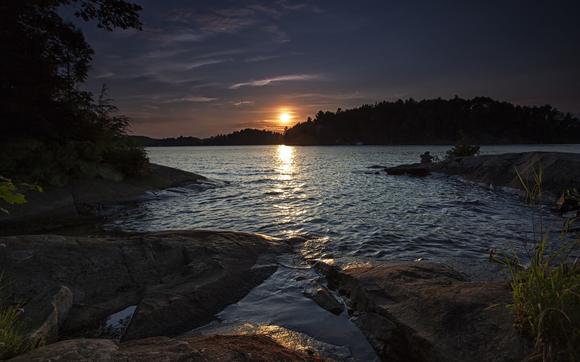 Sunset over a calm lake with rocky shore HD Wallpaper