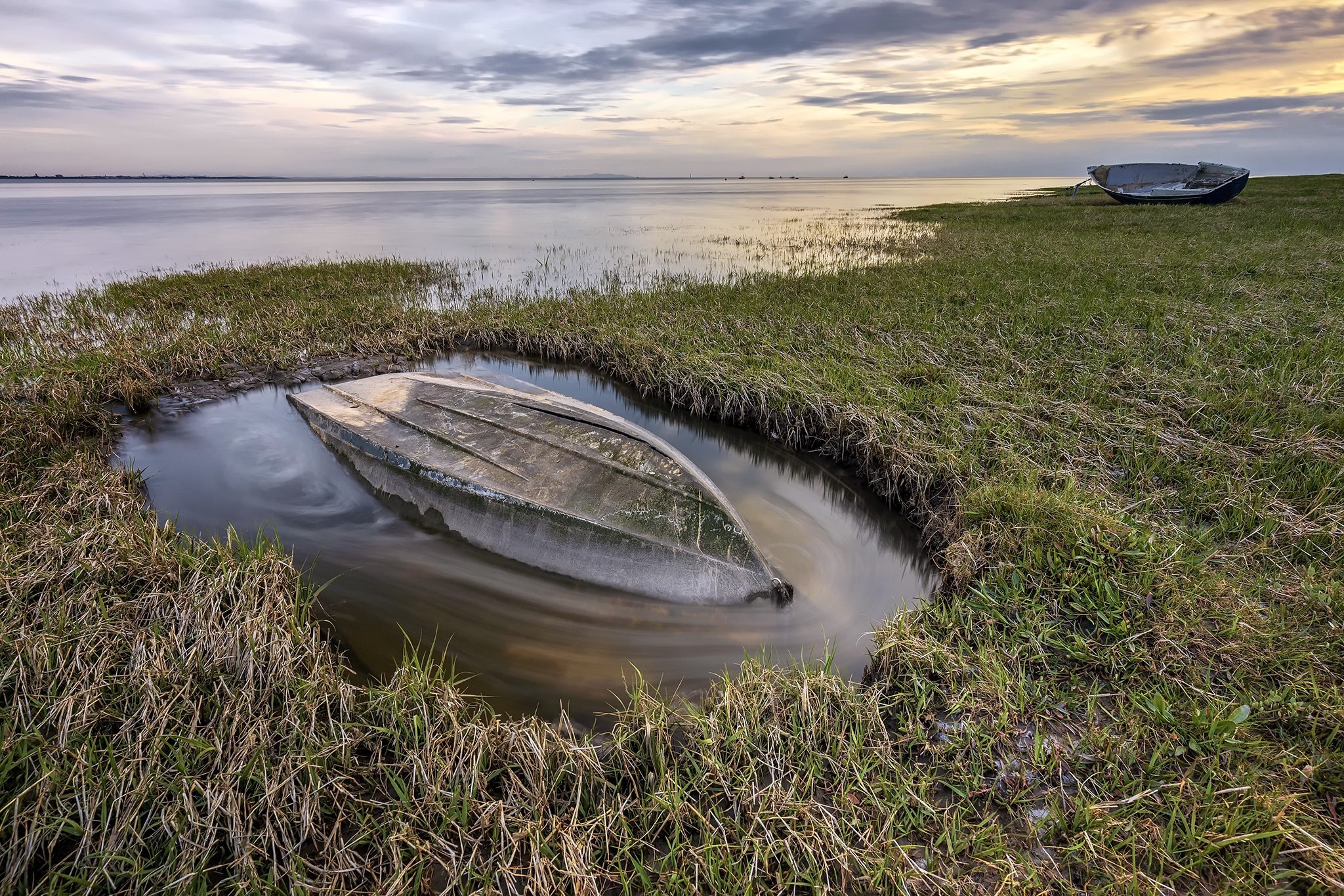 Upside down boat in water by grassy shore HD Wallpaper