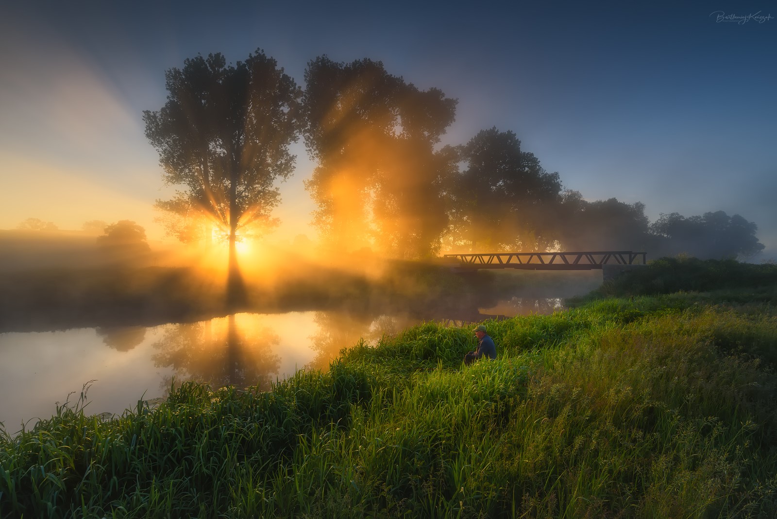 Sunrise over a river with a lone fisherman and a bridge HD Wallpaper