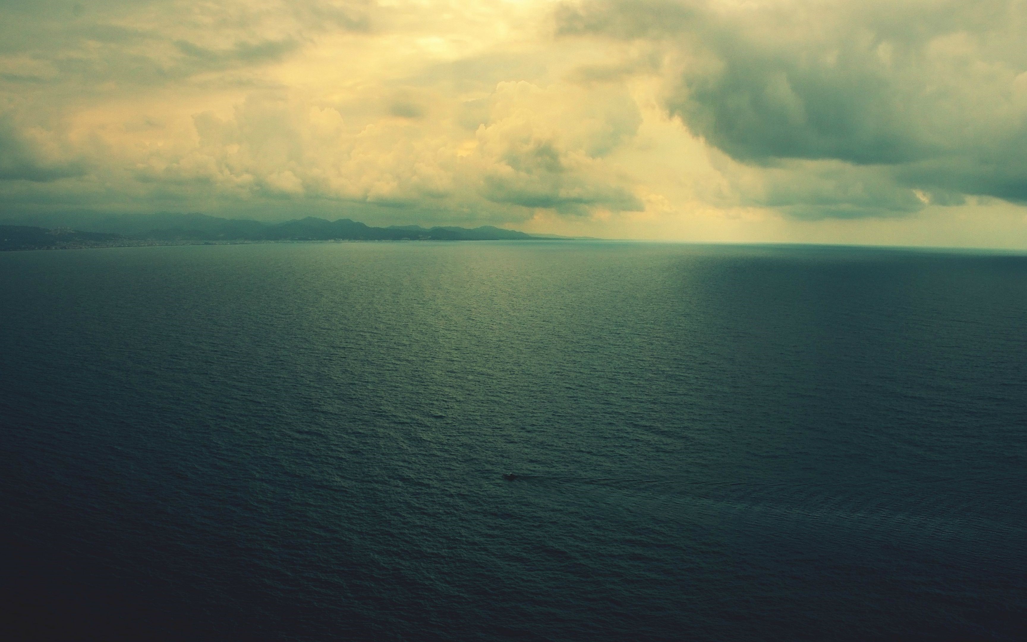 Aerial view of sea under cloudy sky with distant land HD Wallpaper