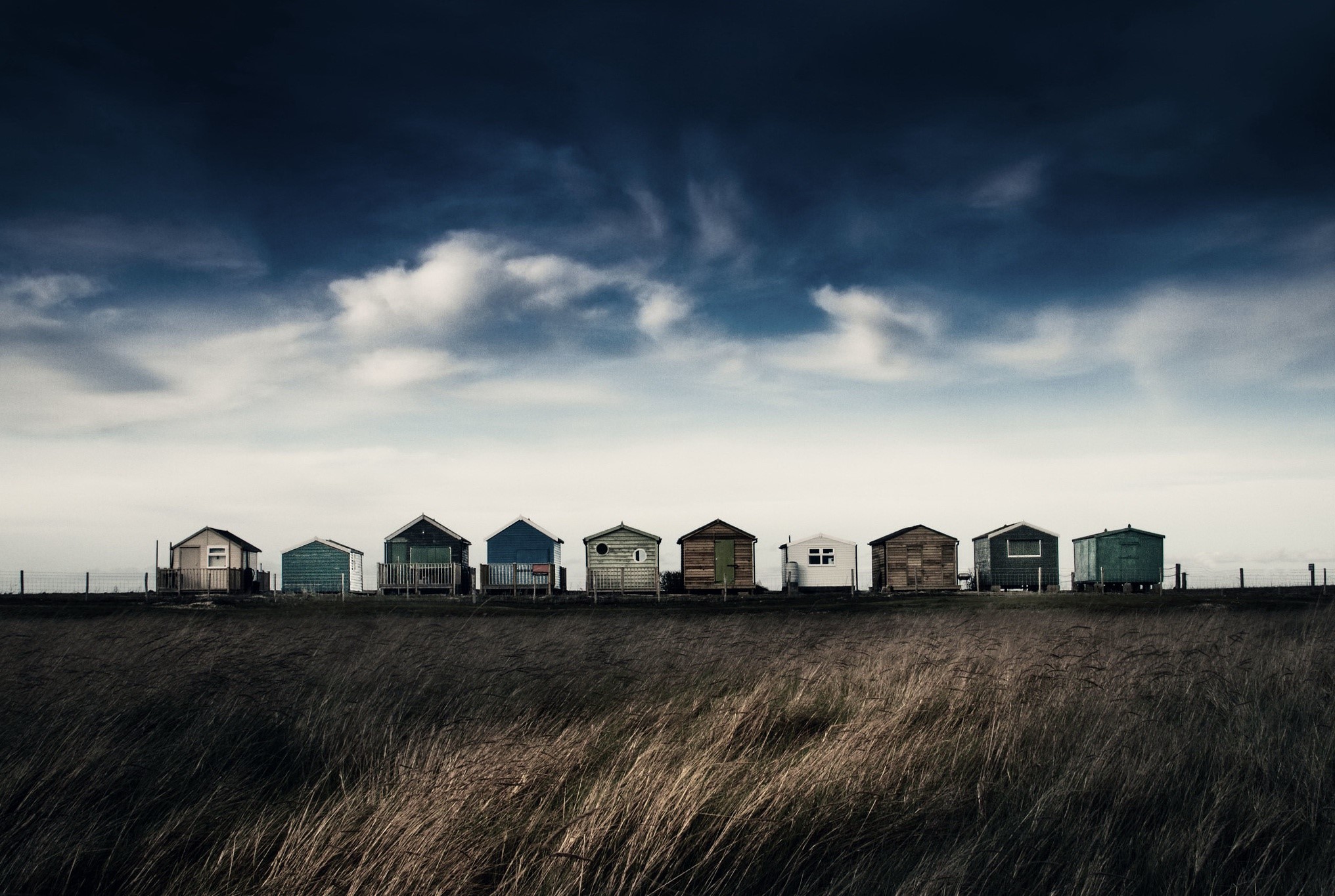 Beach huts under a dramatic sky HD Wallpaper