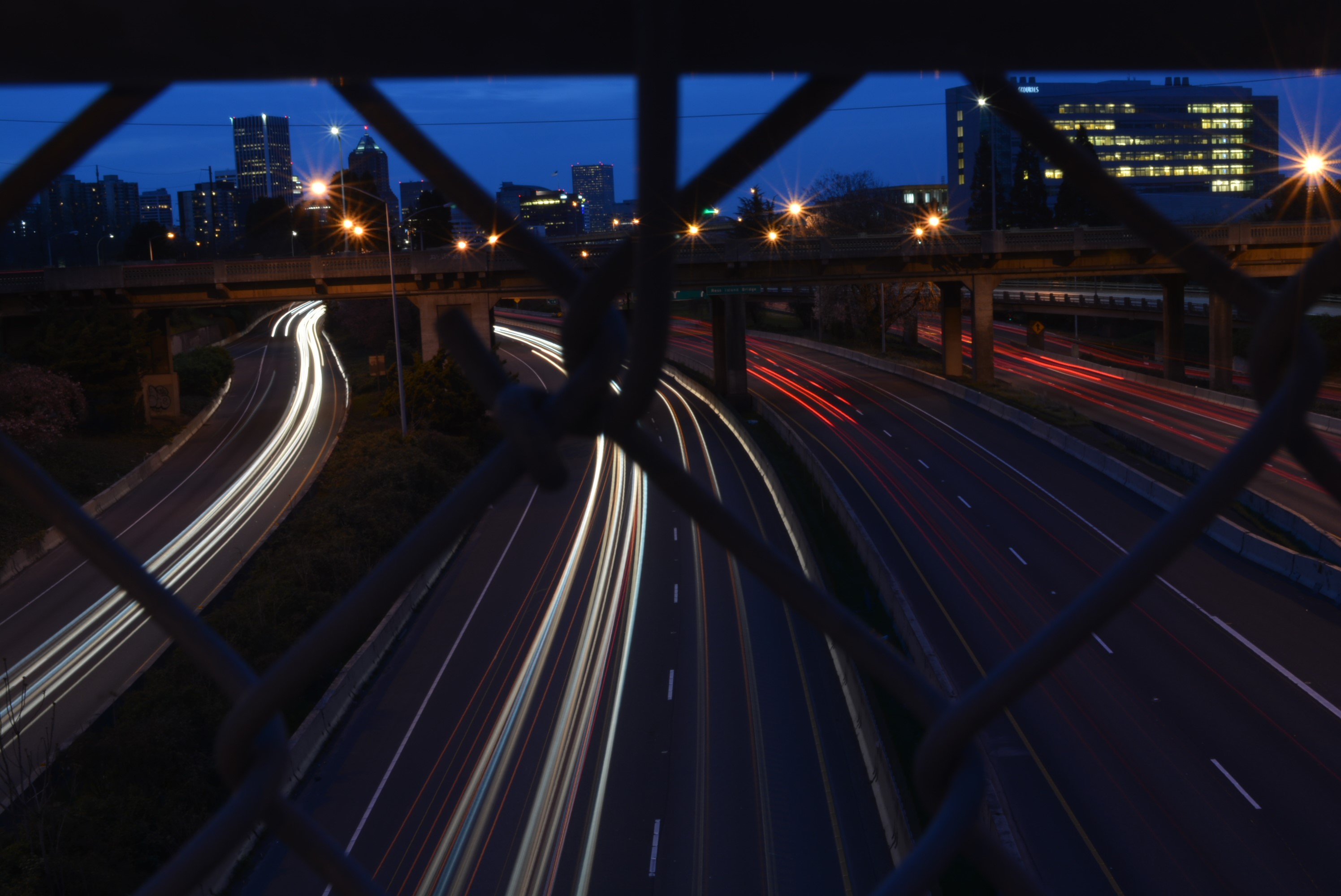 Light trails on a highway at night with city skyline HD Wallpaper