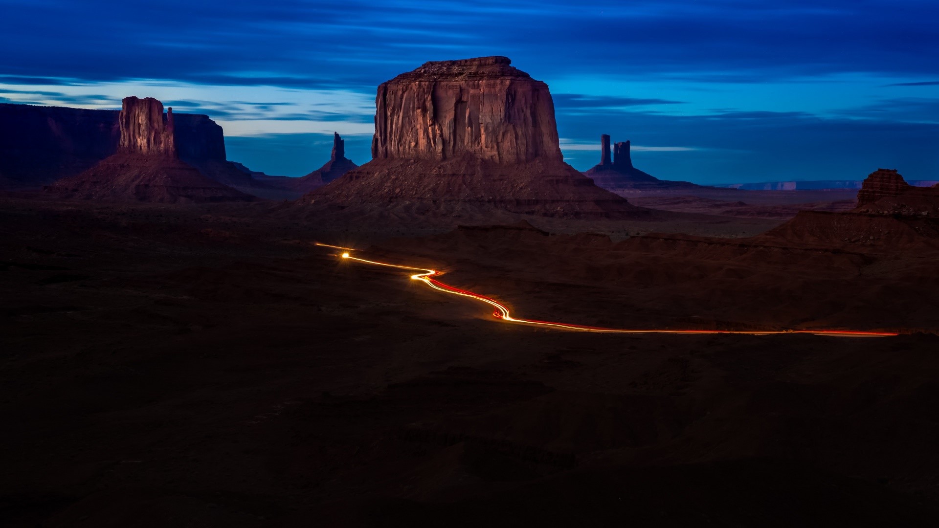 Long exposure of Monument Valley at dusk with car light trails HD Wallpaper