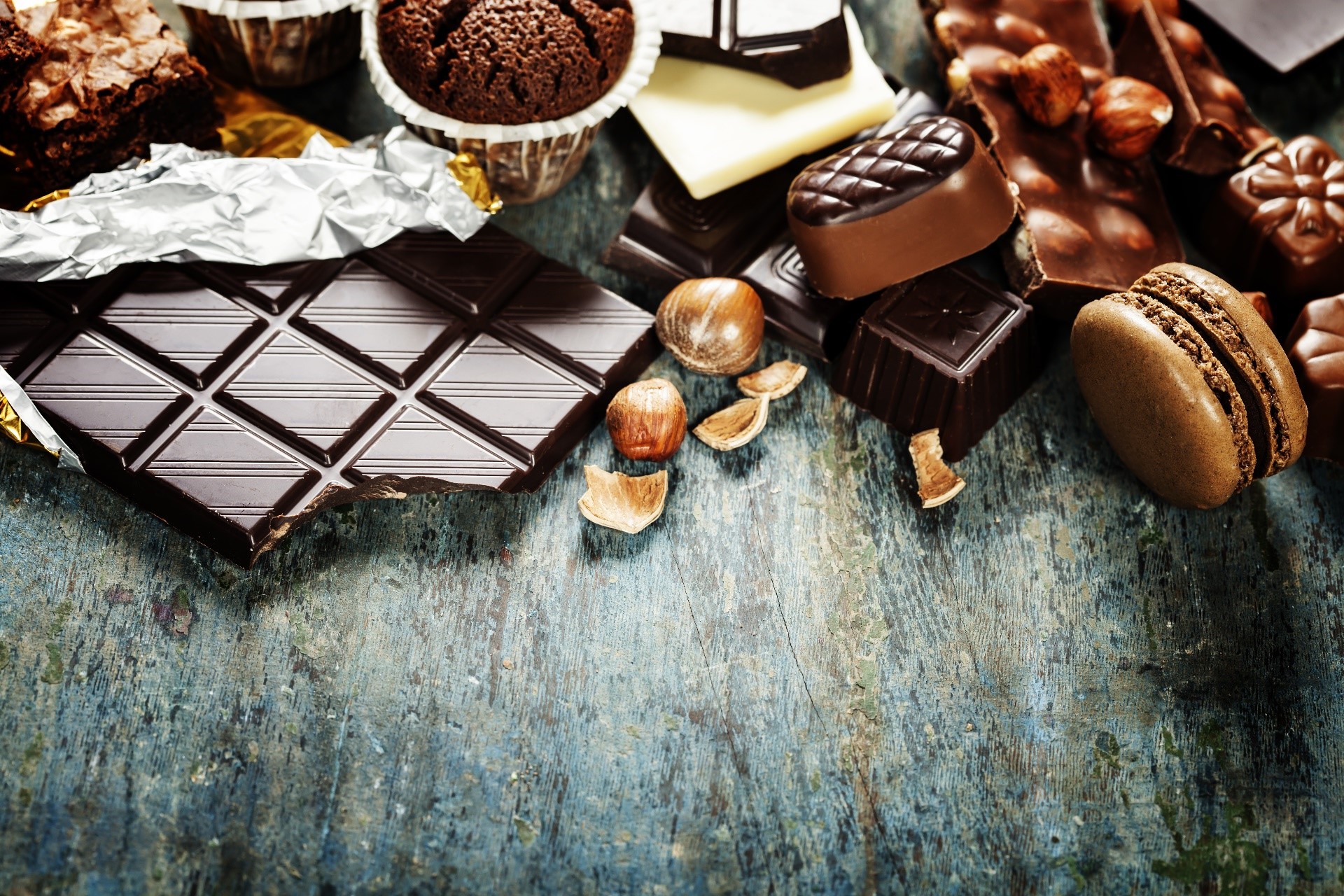 Assortment of chocolates, brownies, and macarons on a wooden surface HD Wallpaper