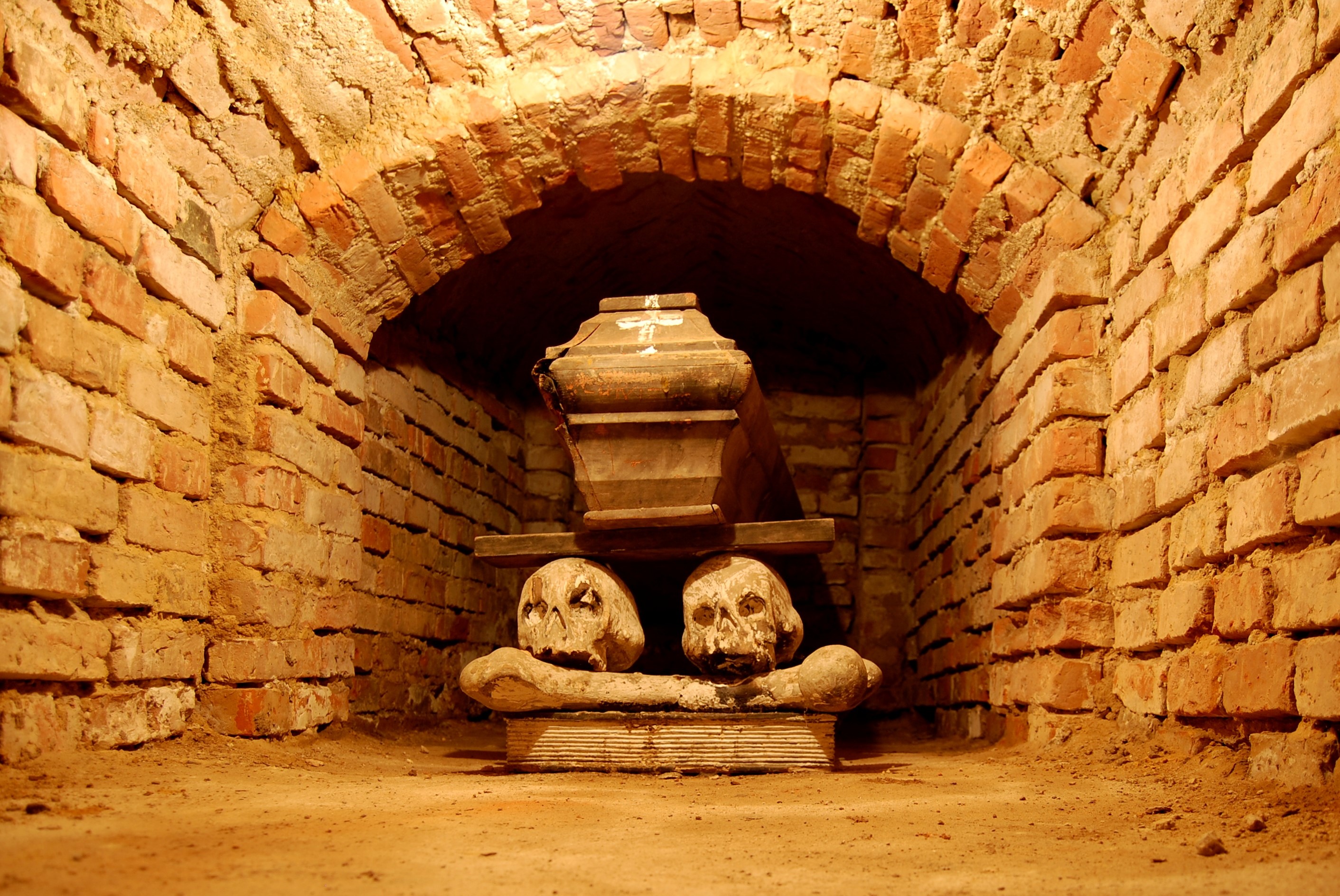 Tomb with coffin and skulls in brick crypt HD Wallpaper