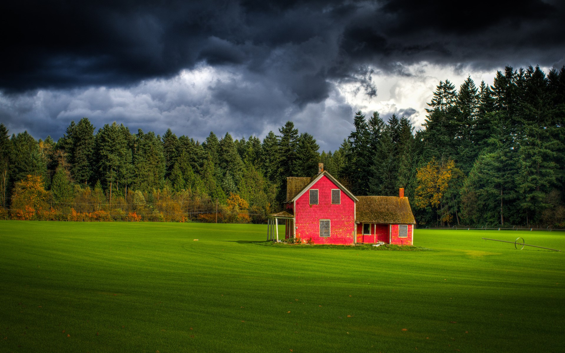Red house in a green field with a forest and stormy sky HD Wallpaper
