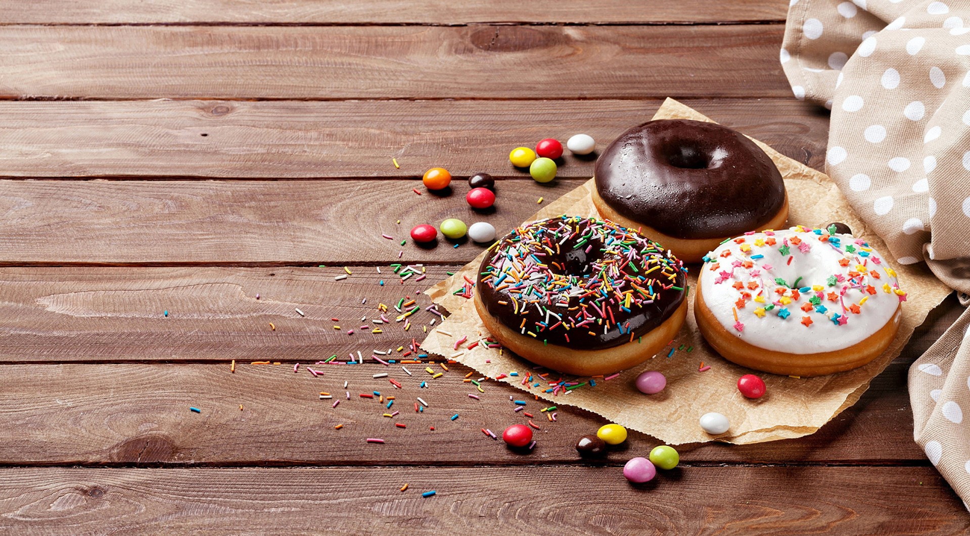 Donuts and candies on a wooden table HD Wallpaper