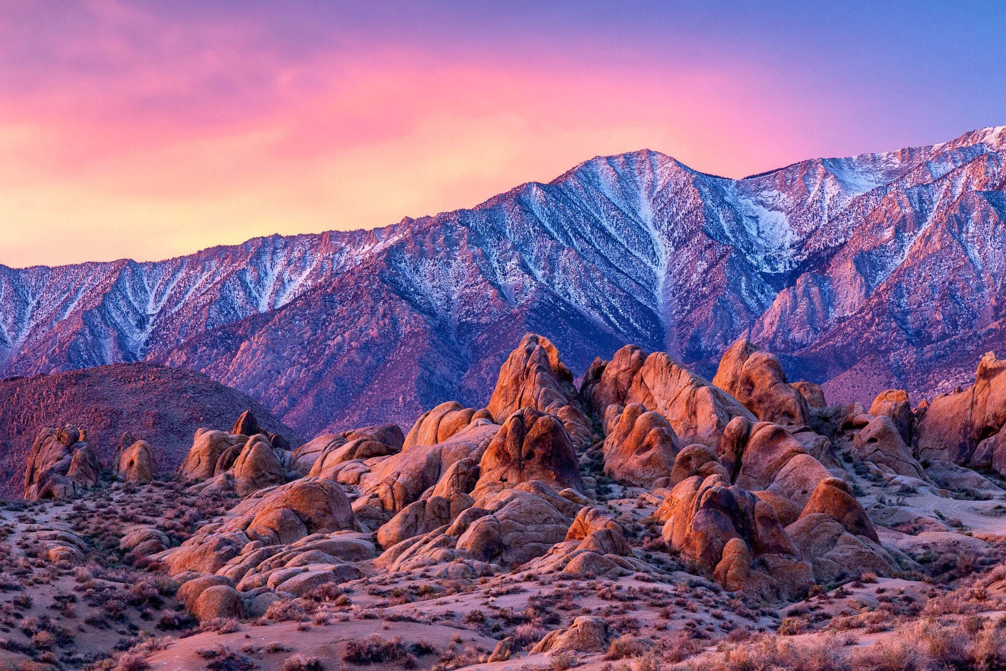 Rocky desert landscape with snow-capped mountains at sunset HD Wallpaper