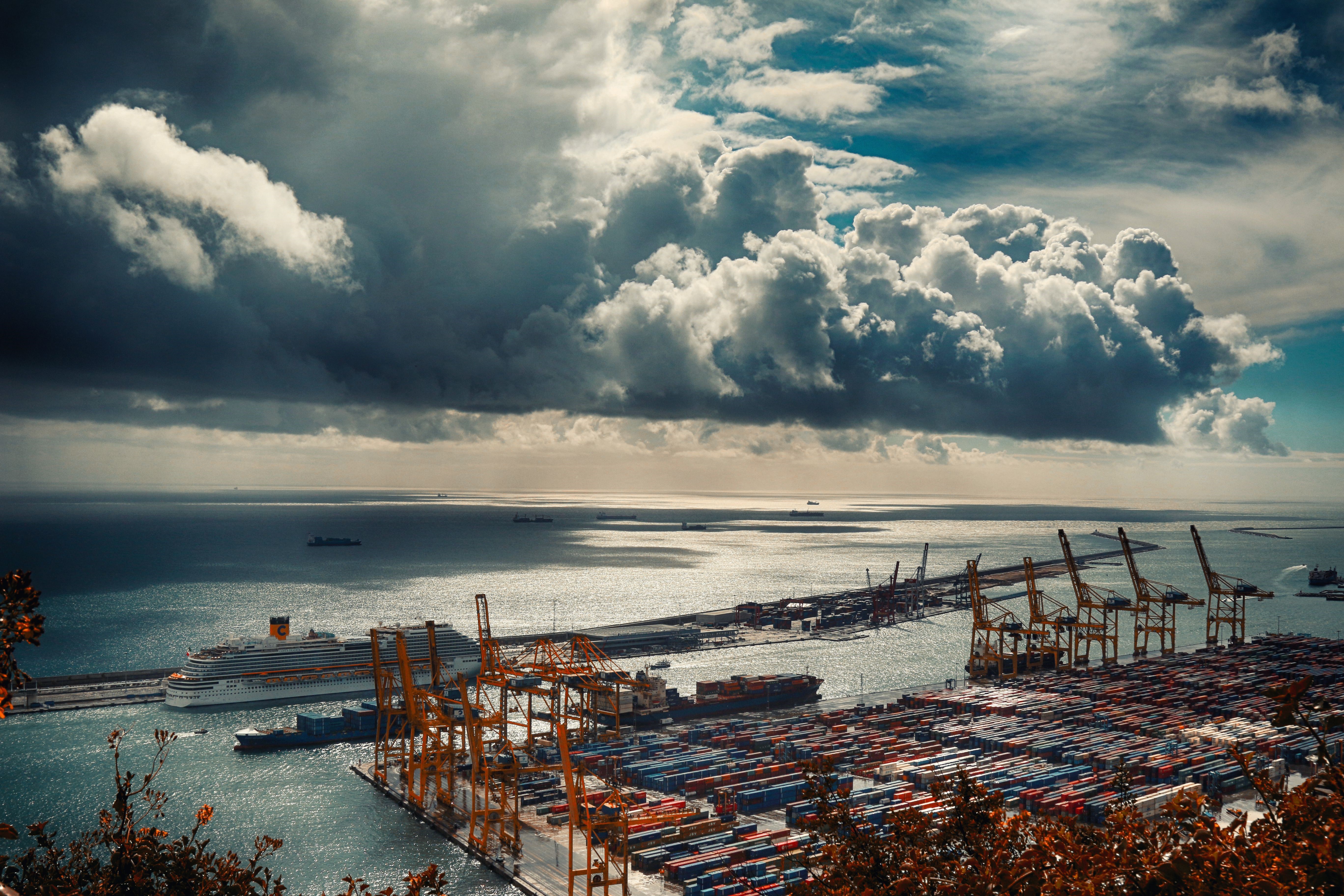Barcelona harbor with cargo containers and cruise ship under stormy clouds HD Wallpaper