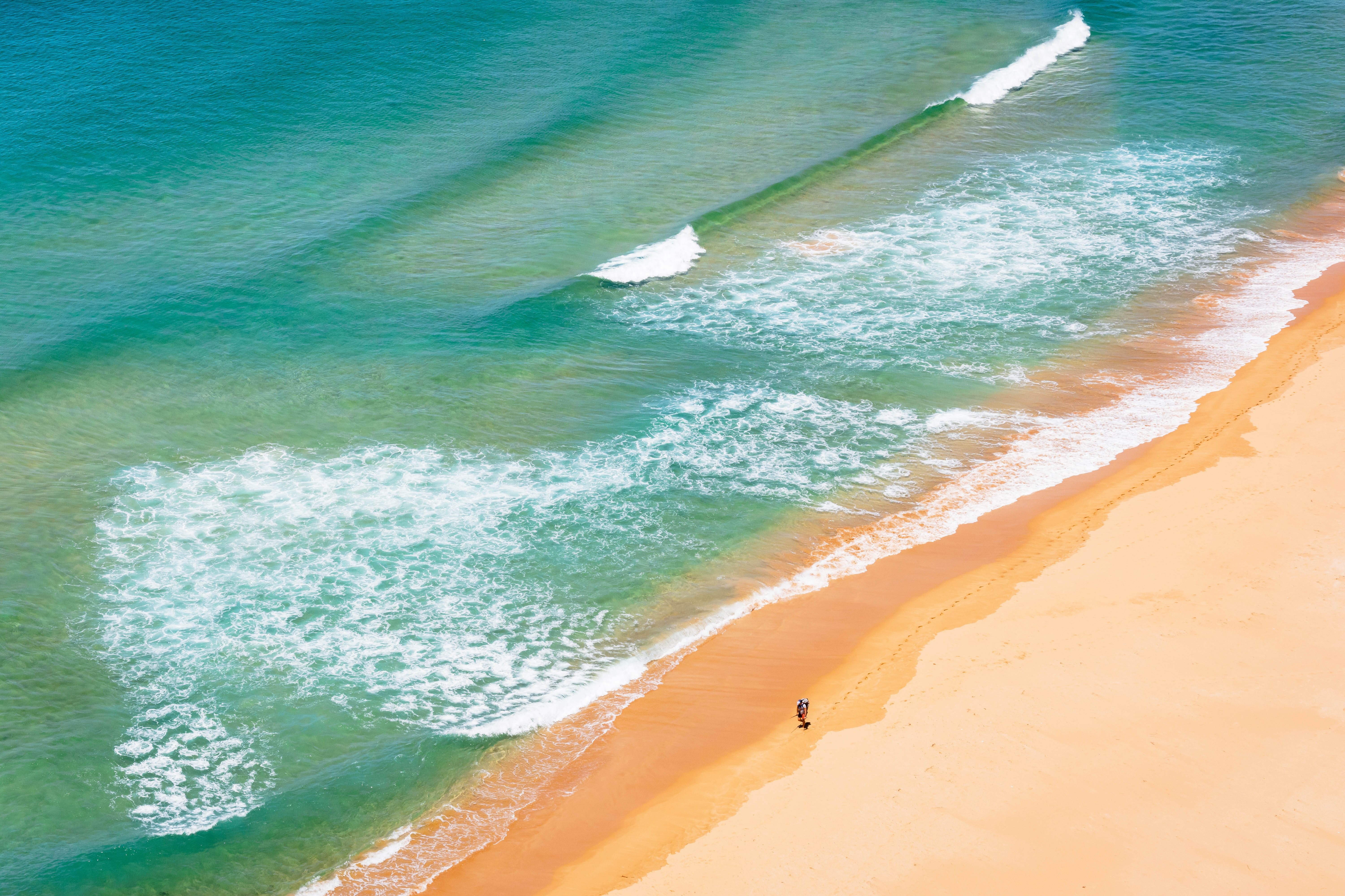 Aerial view of a beach with waves and footprints HD Wallpaper