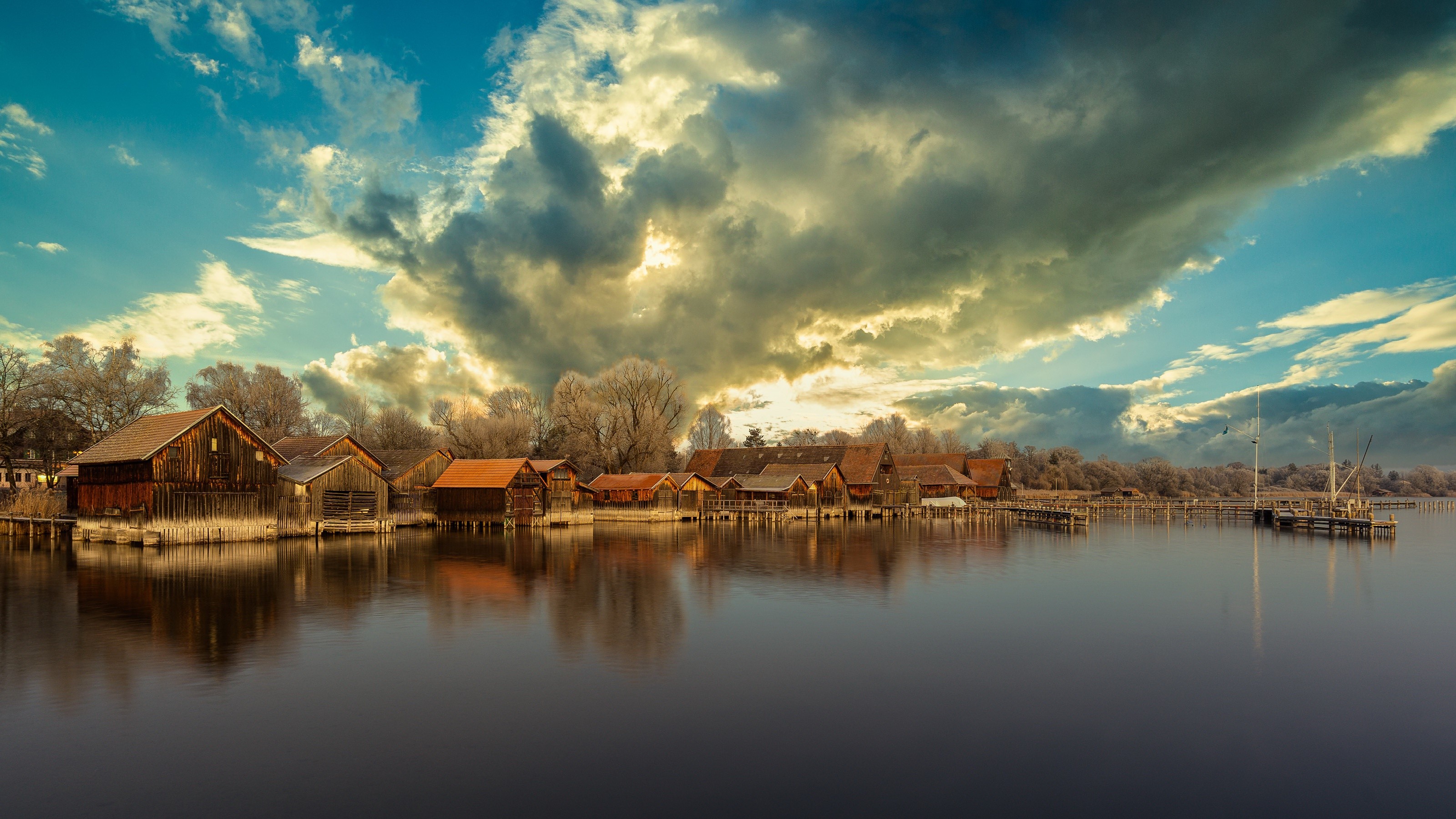 Wooden boathouses on Lake Ammer, Germany under dramatic clouds HD Wallpaper