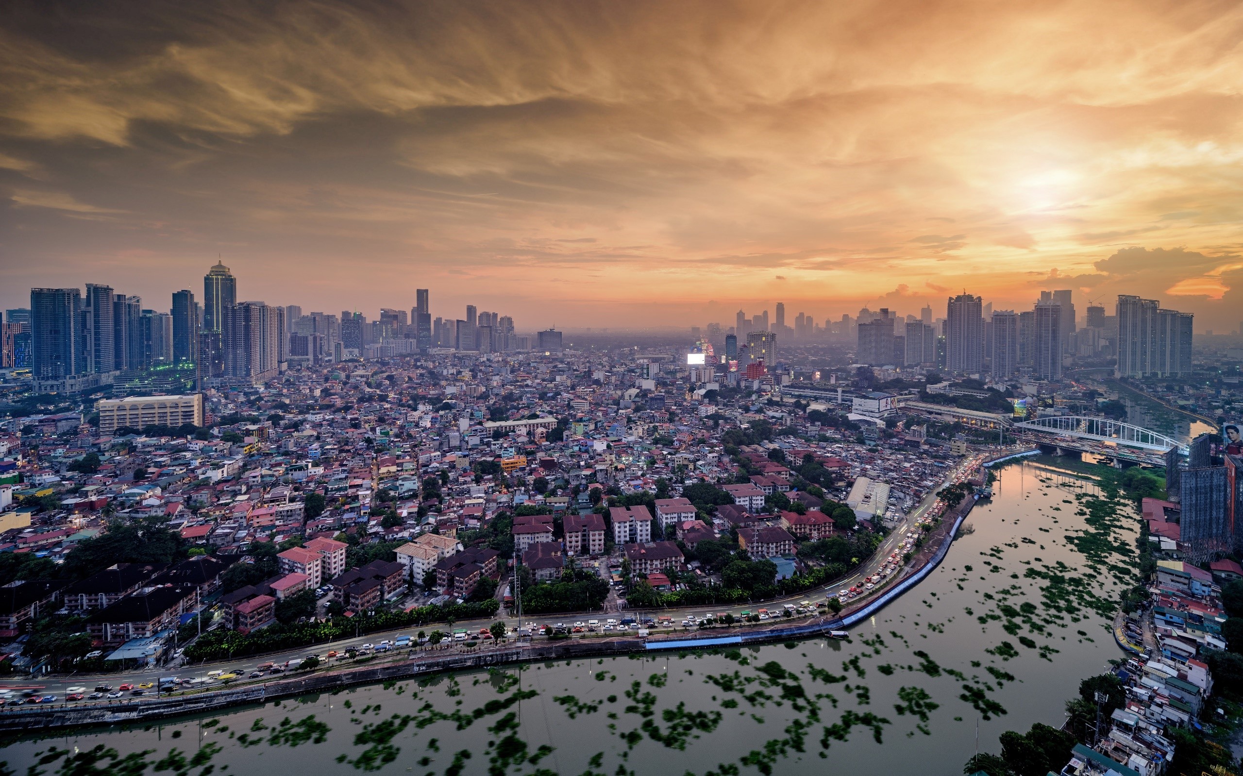 Manila cityscape at sunset with river and buildings HD Wallpaper