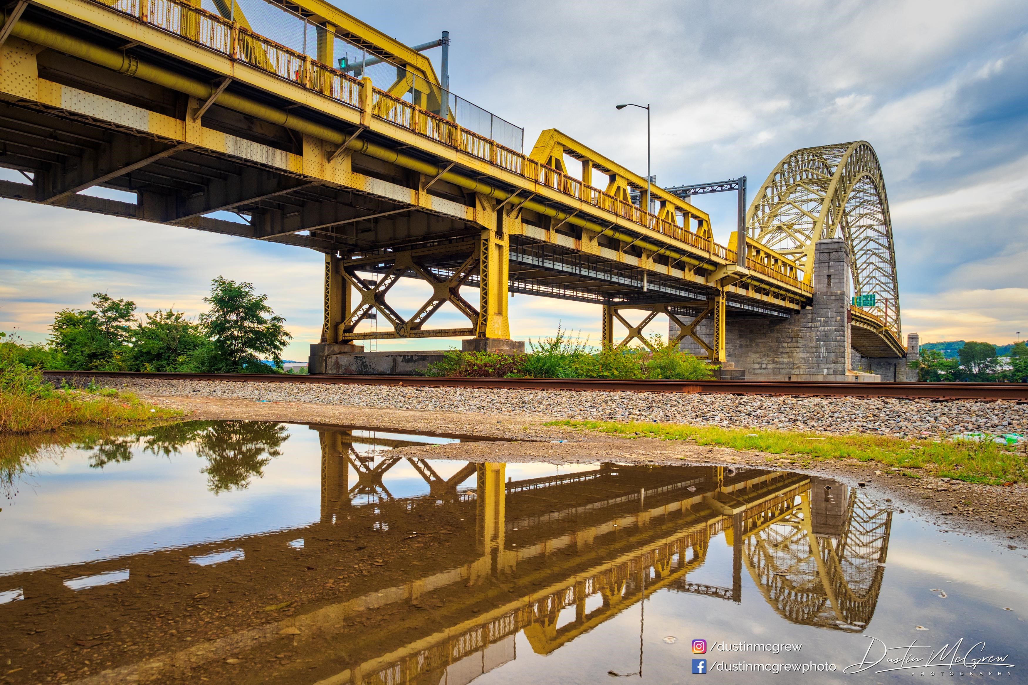 Yellow bridge over railroad tracks with reflection in water HD Wallpaper