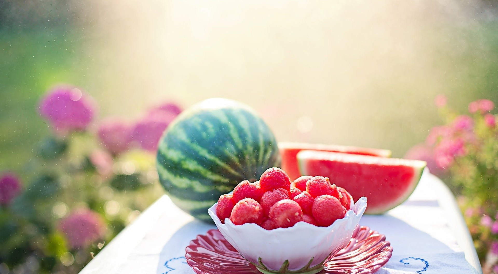 Watermelon and berries on a table with flowers HD Wallpaper