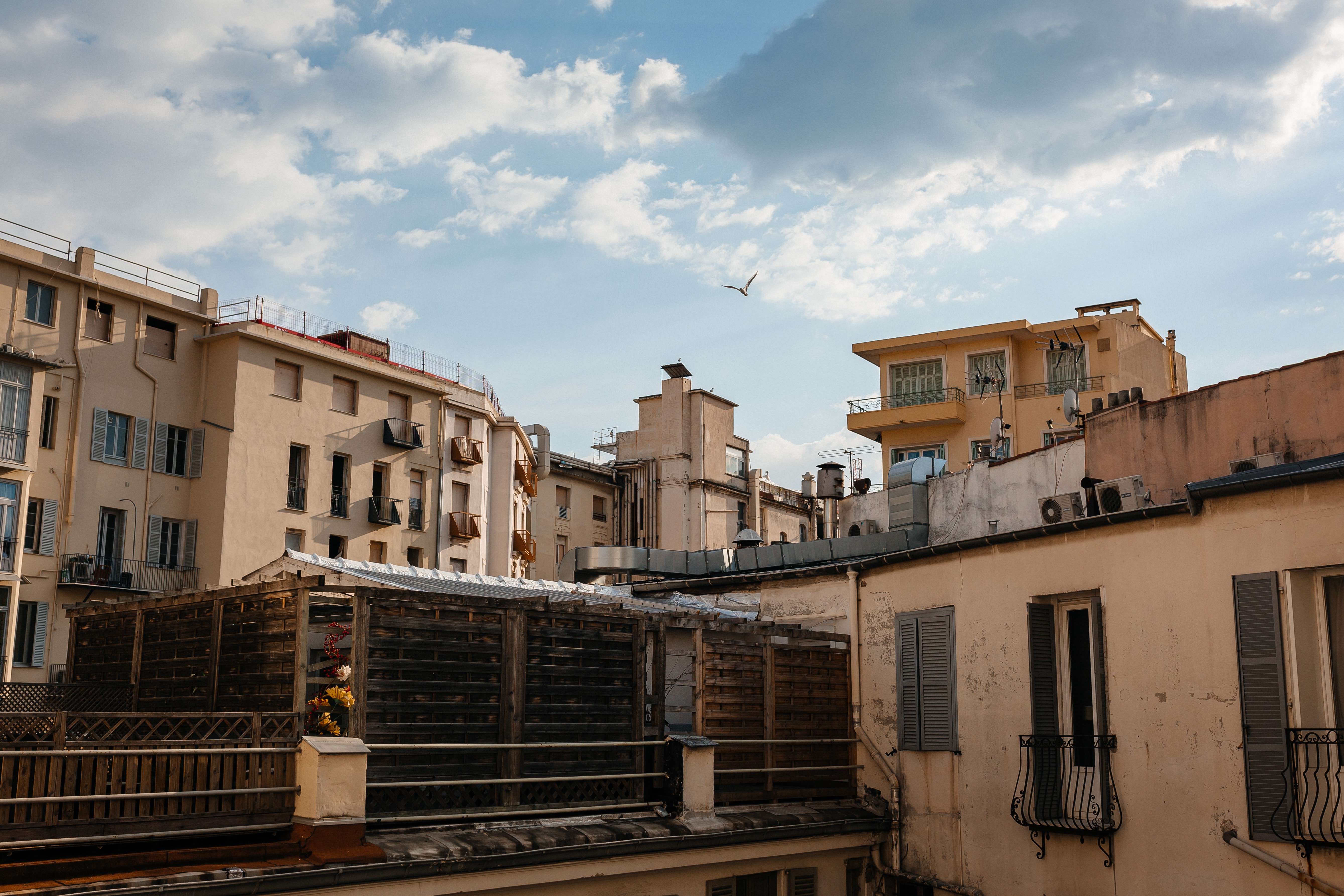 Rooftops and buildings in France with clouds and a bird HD Wallpaper