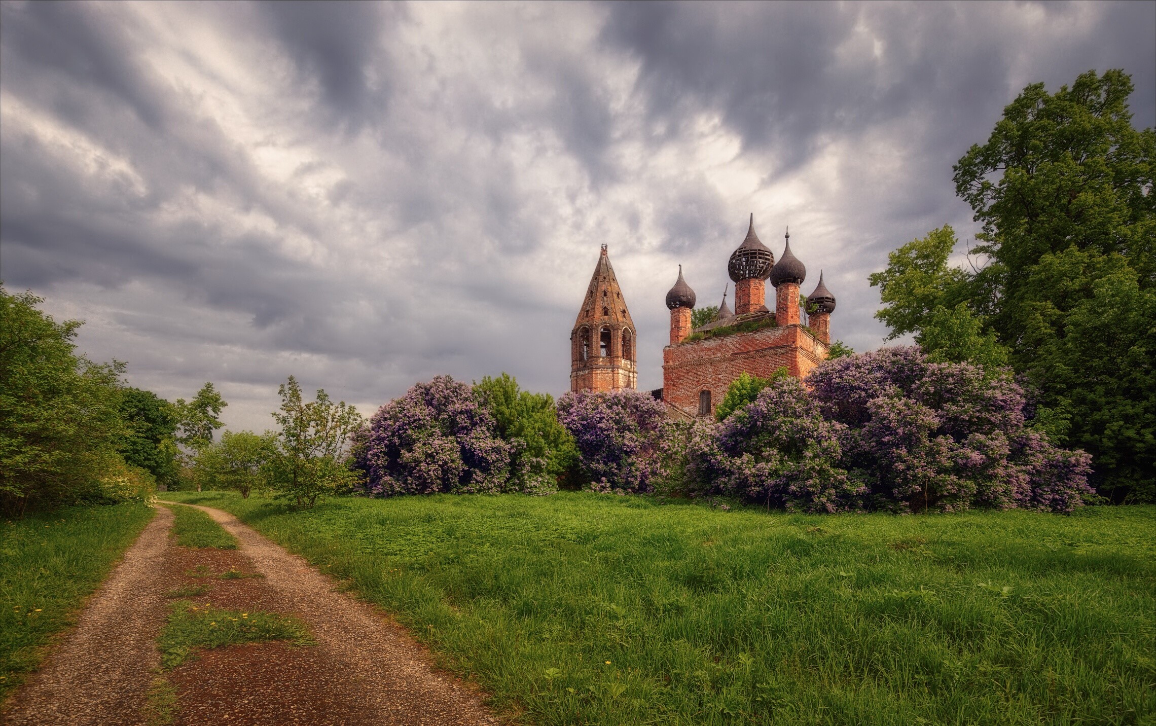 Abandoned church with onion domes and bell tower surrounded by lilac bushes HD Wallpaper