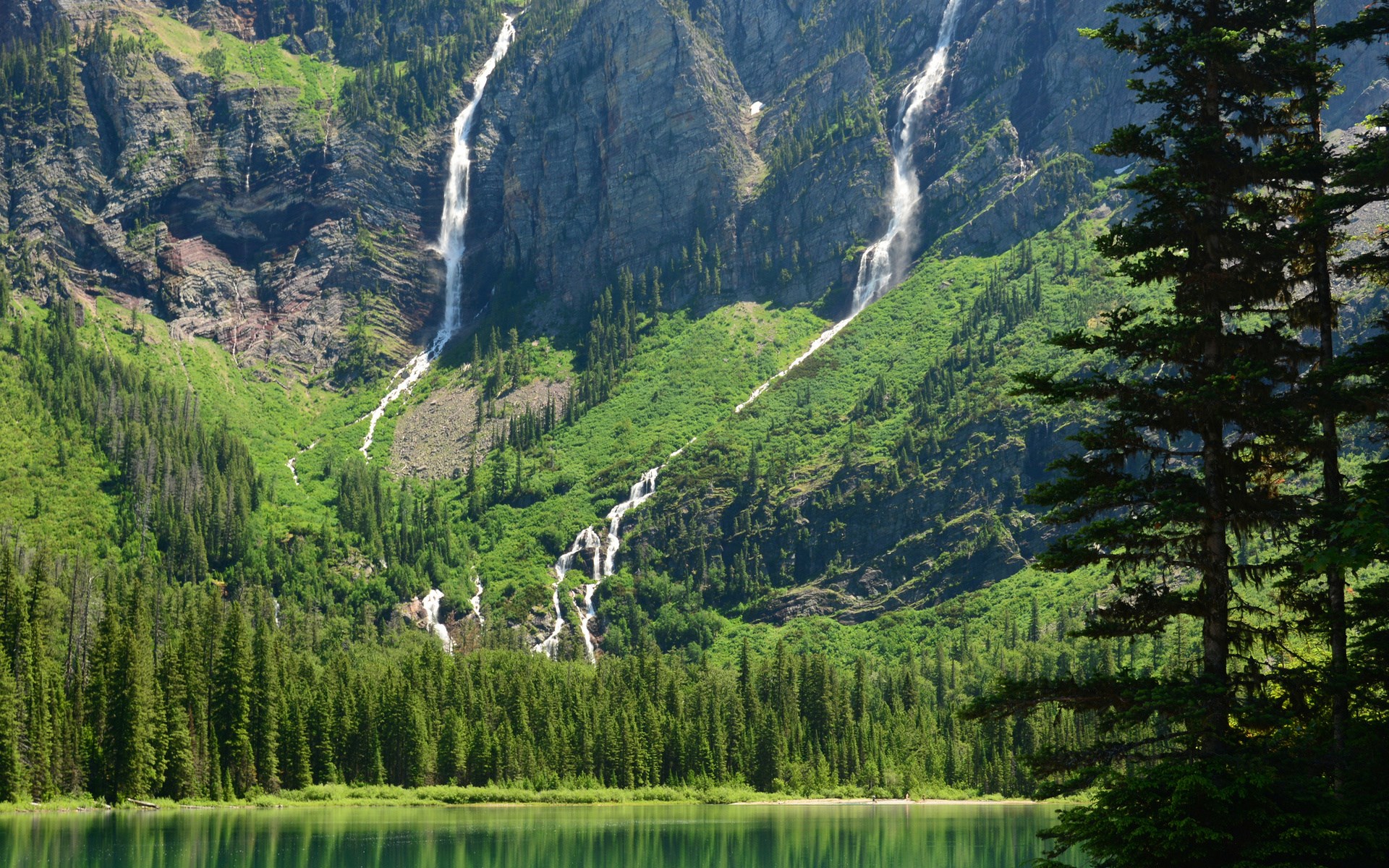 Waterfalls cascading down a mountain into a lake HD Wallpaper