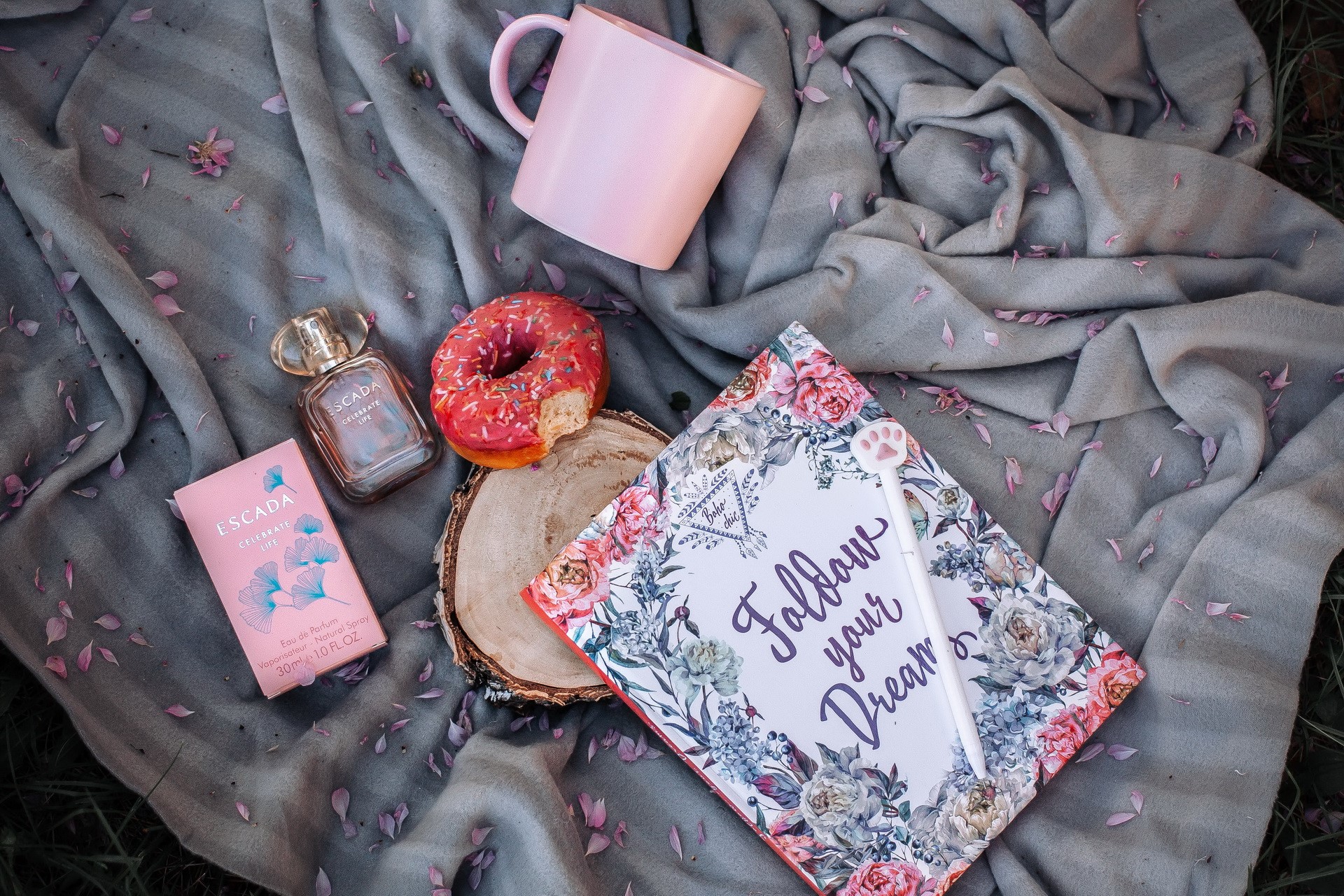 Escada perfume, donut, mug, and notebook on blanket HD Wallpaper