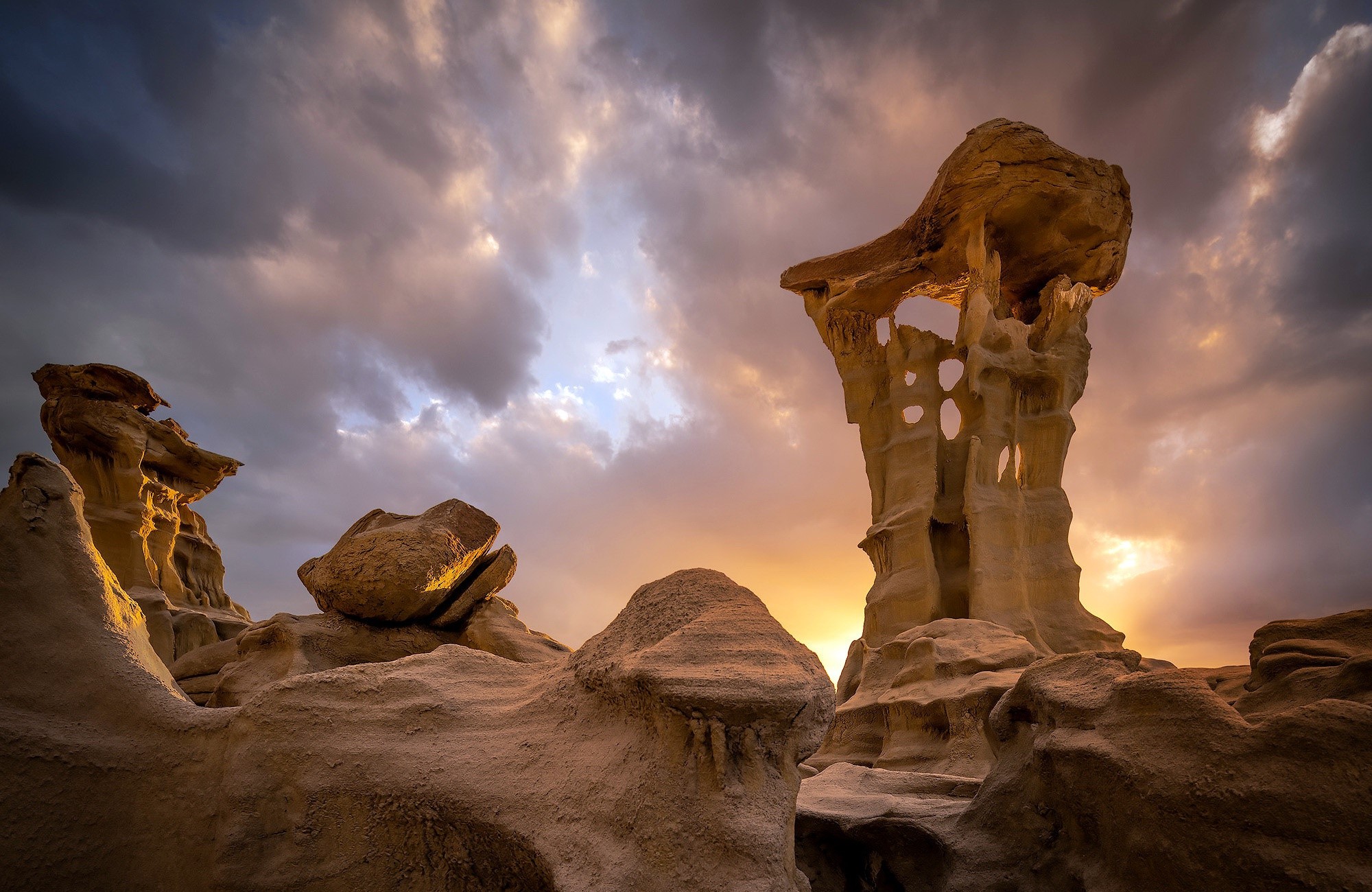 Rock formations under a dramatic cloudy sky at sunset HD Wallpaper