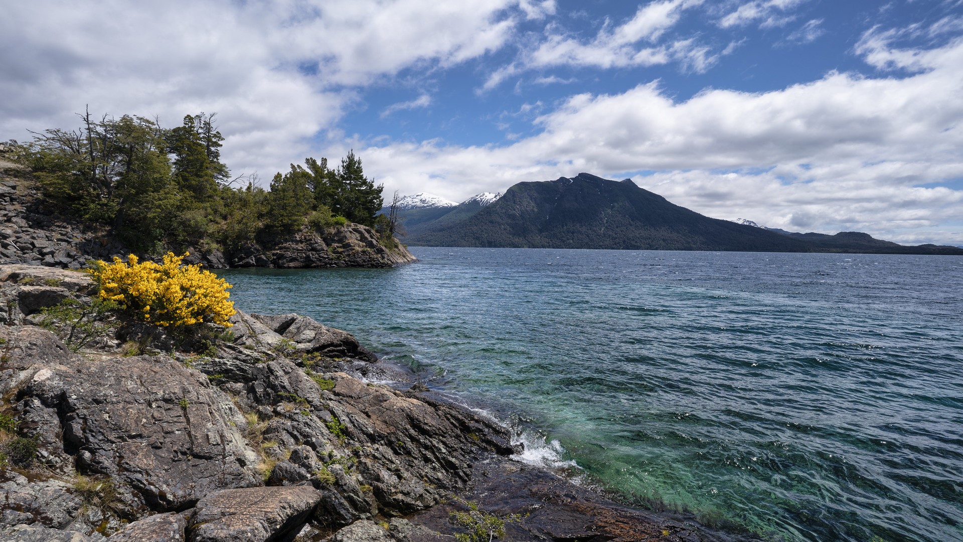 Rocky shore of Nahuel Huapi Lake with mountains HD Wallpaper