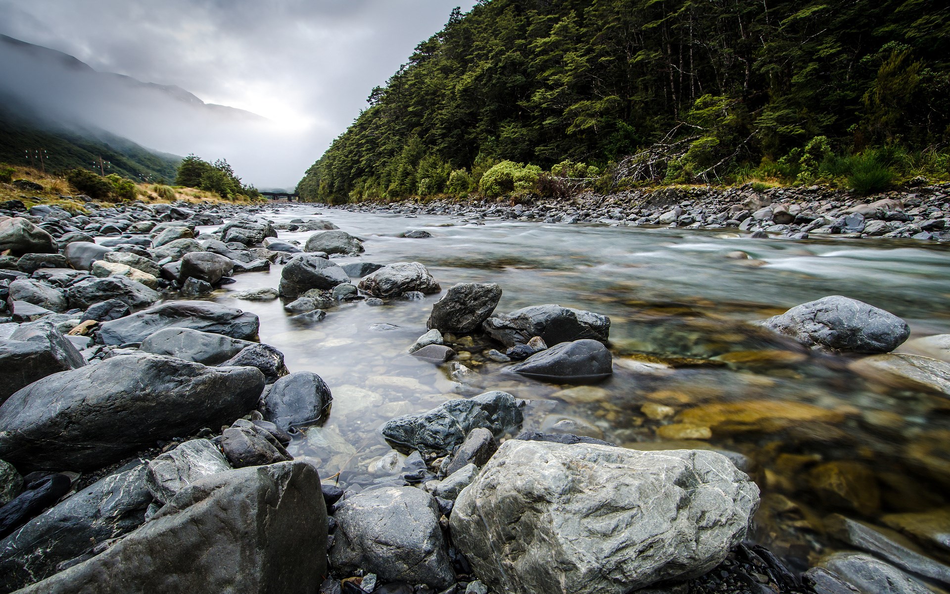 River flowing through a rocky landscape with a forest HD Wallpaper