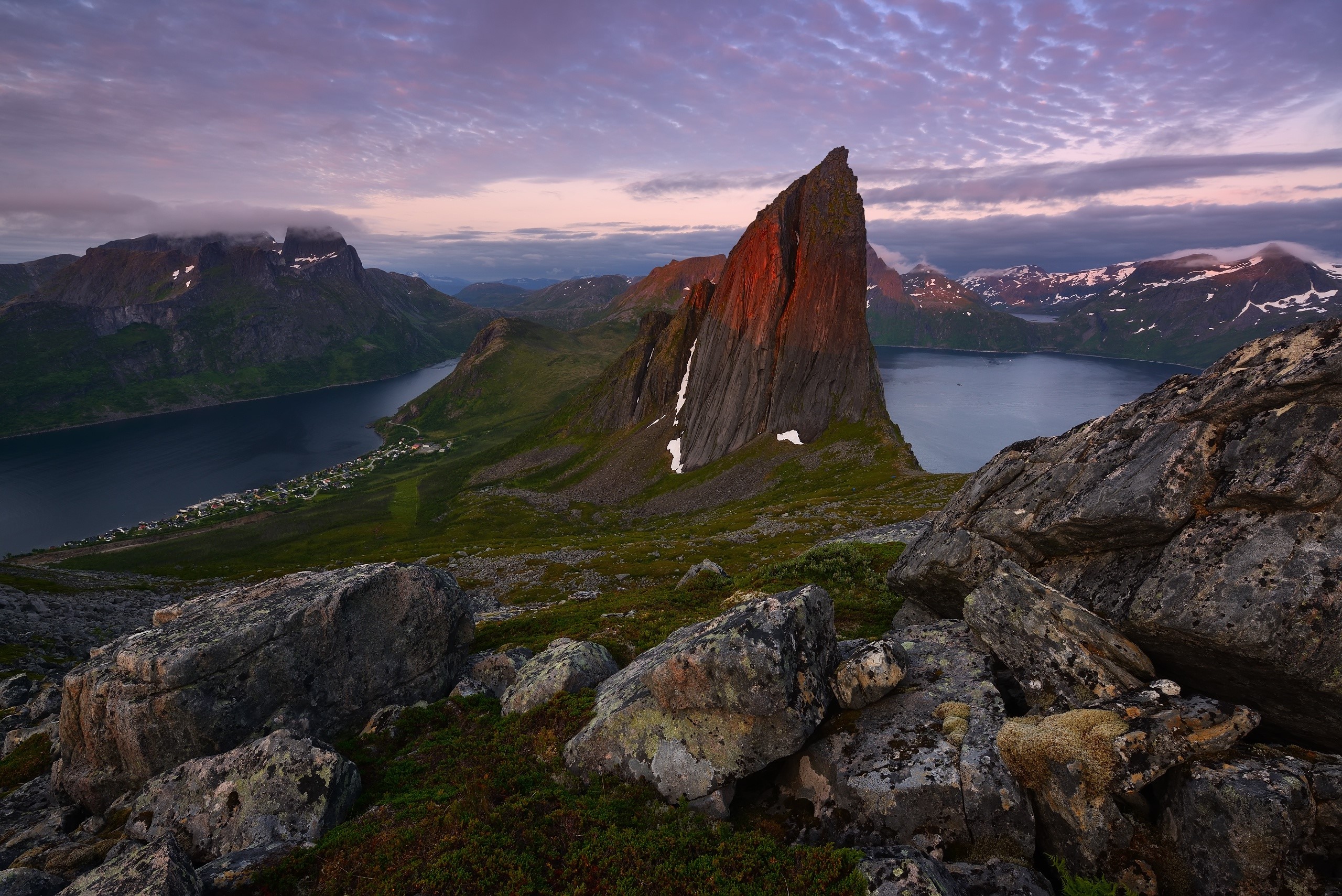 Sharp mountain peak illuminated by sunset over a fjord in Norway HD Wallpaper