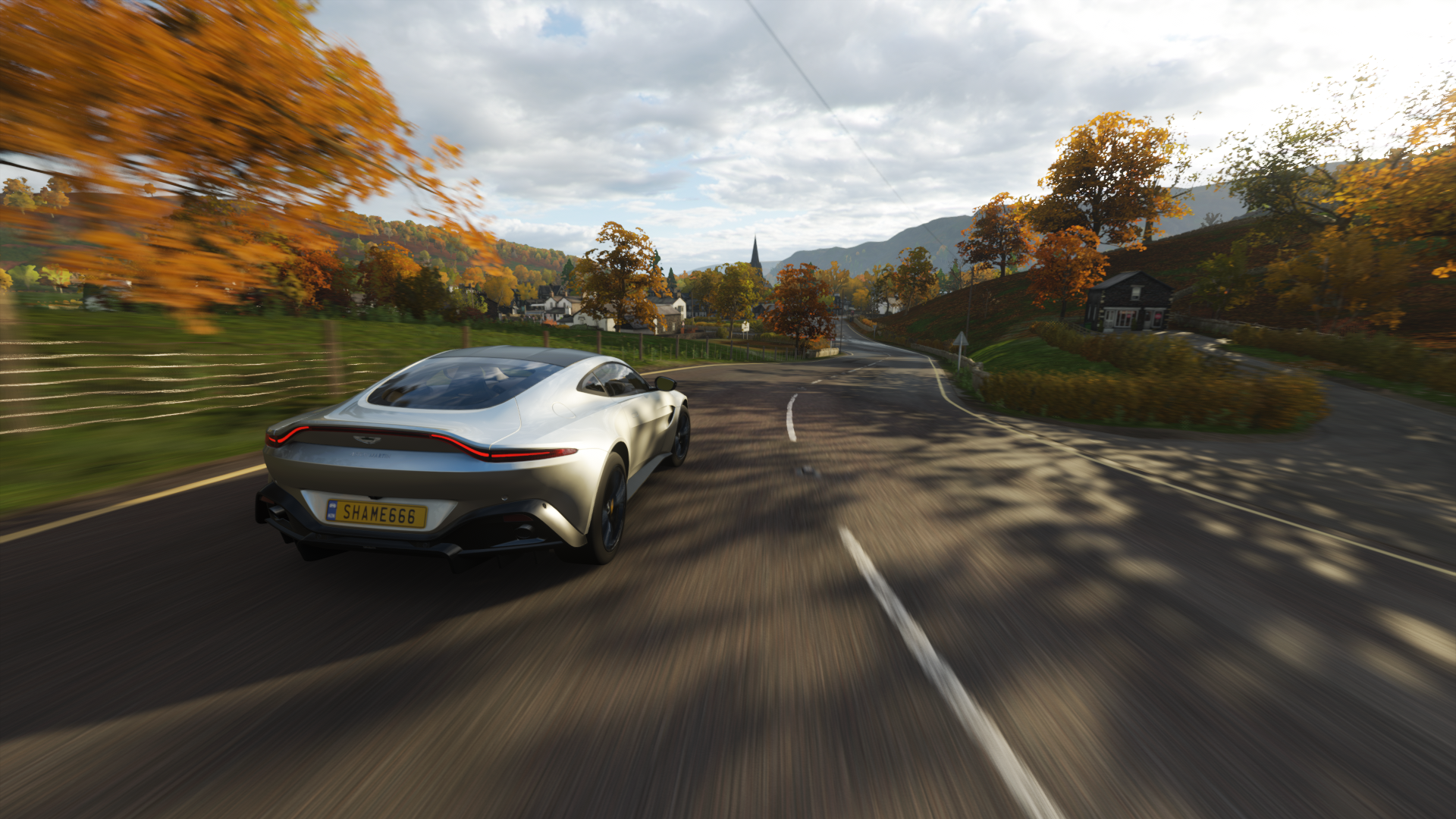 Silver Aston Martin driving on a road in autumn HD Wallpaper