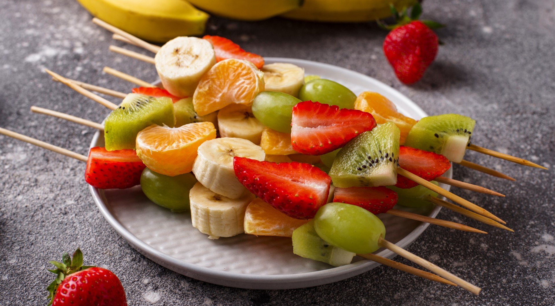 Fruit skewers with strawberries, kiwi, bananas, and tangerines HD Wallpaper