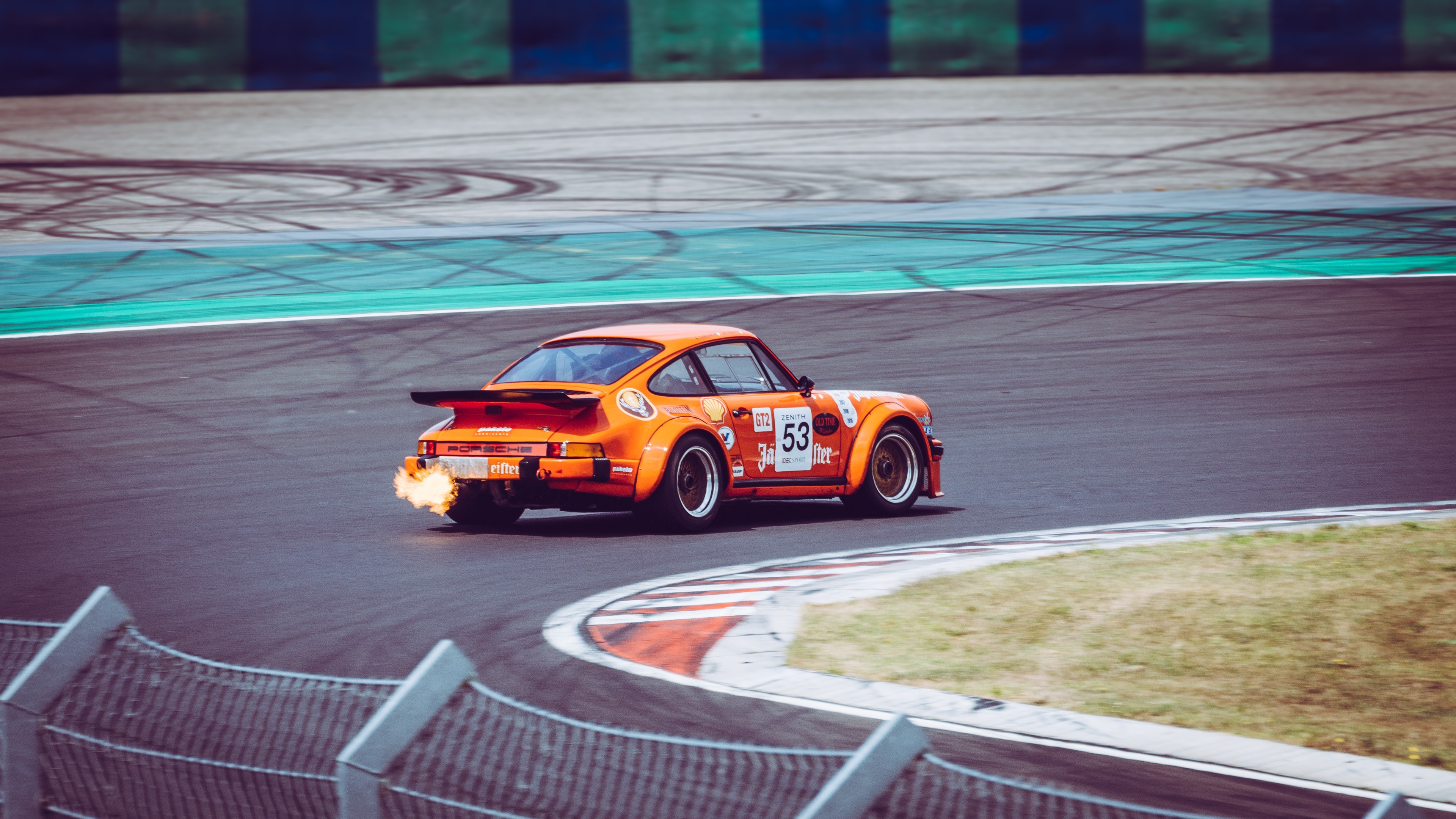 Orange Porsche 911 race car with exhaust flare on track HD Wallpaper