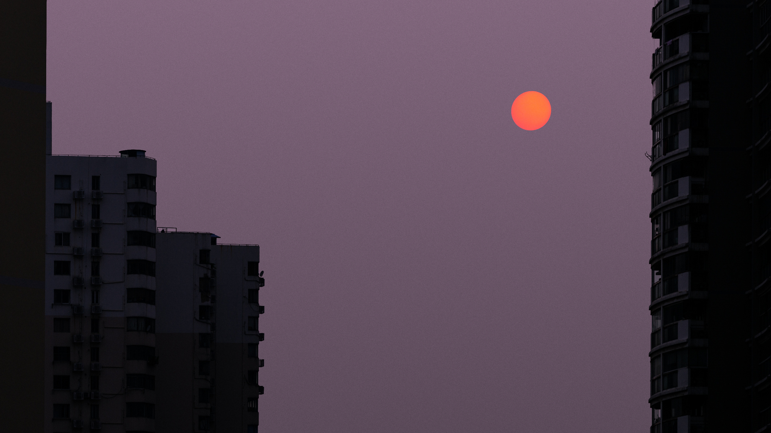 Apartment buildings at dusk with a red sun HD Wallpaper