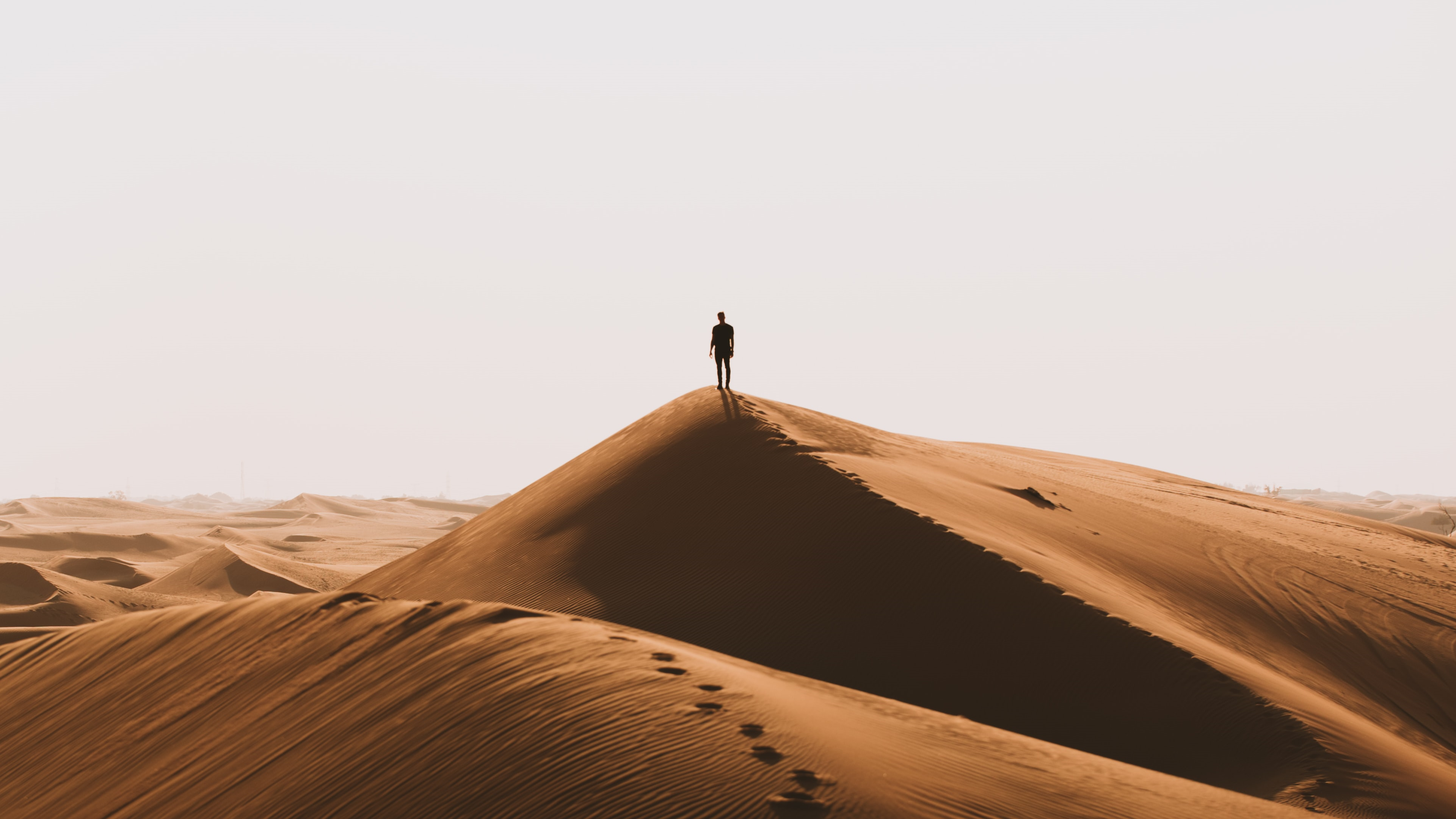 Man standing on a sand dune in the desert HD Wallpaper