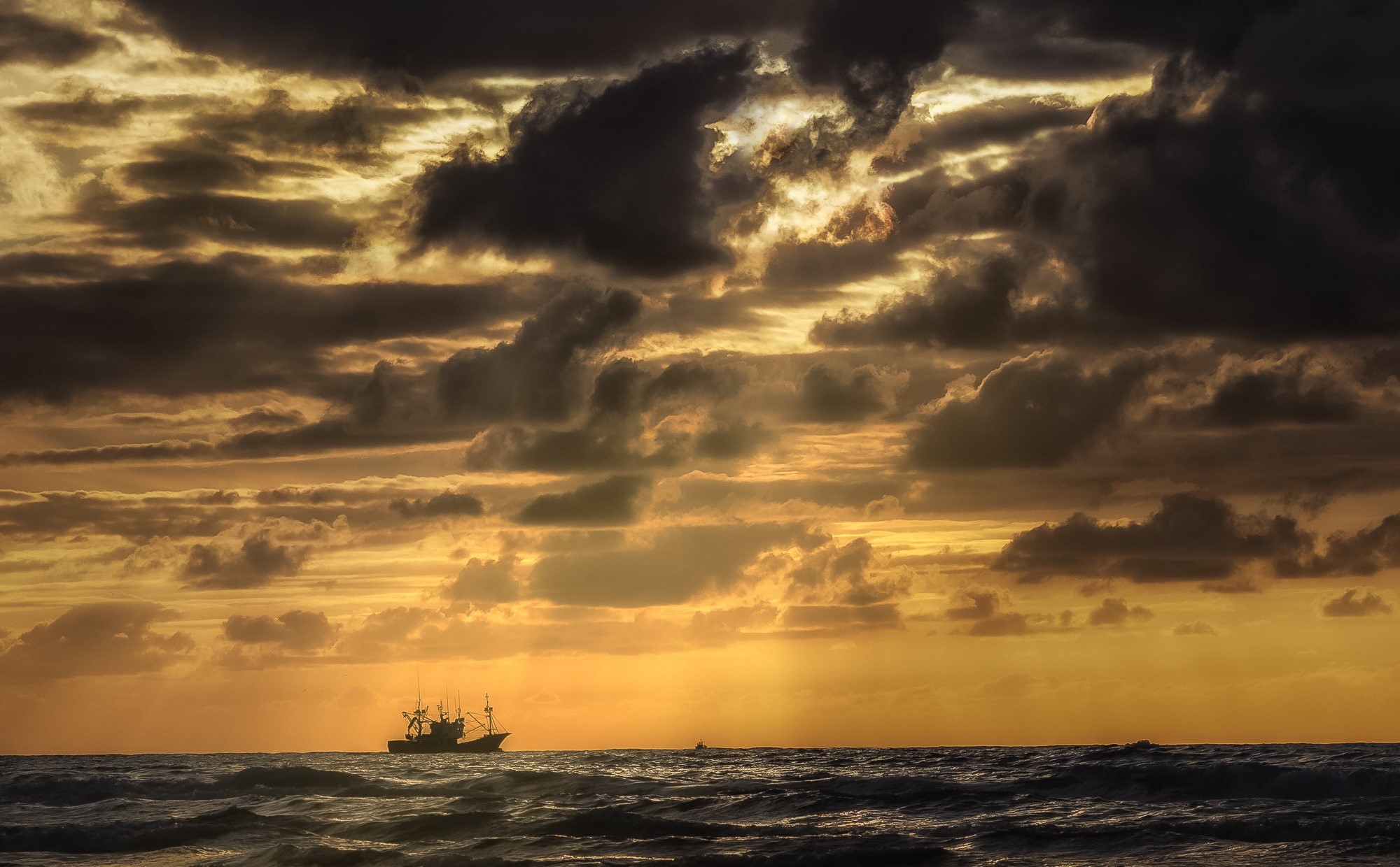 Fishing boat on the sea at sunset with dramatic clouds HD Wallpaper
