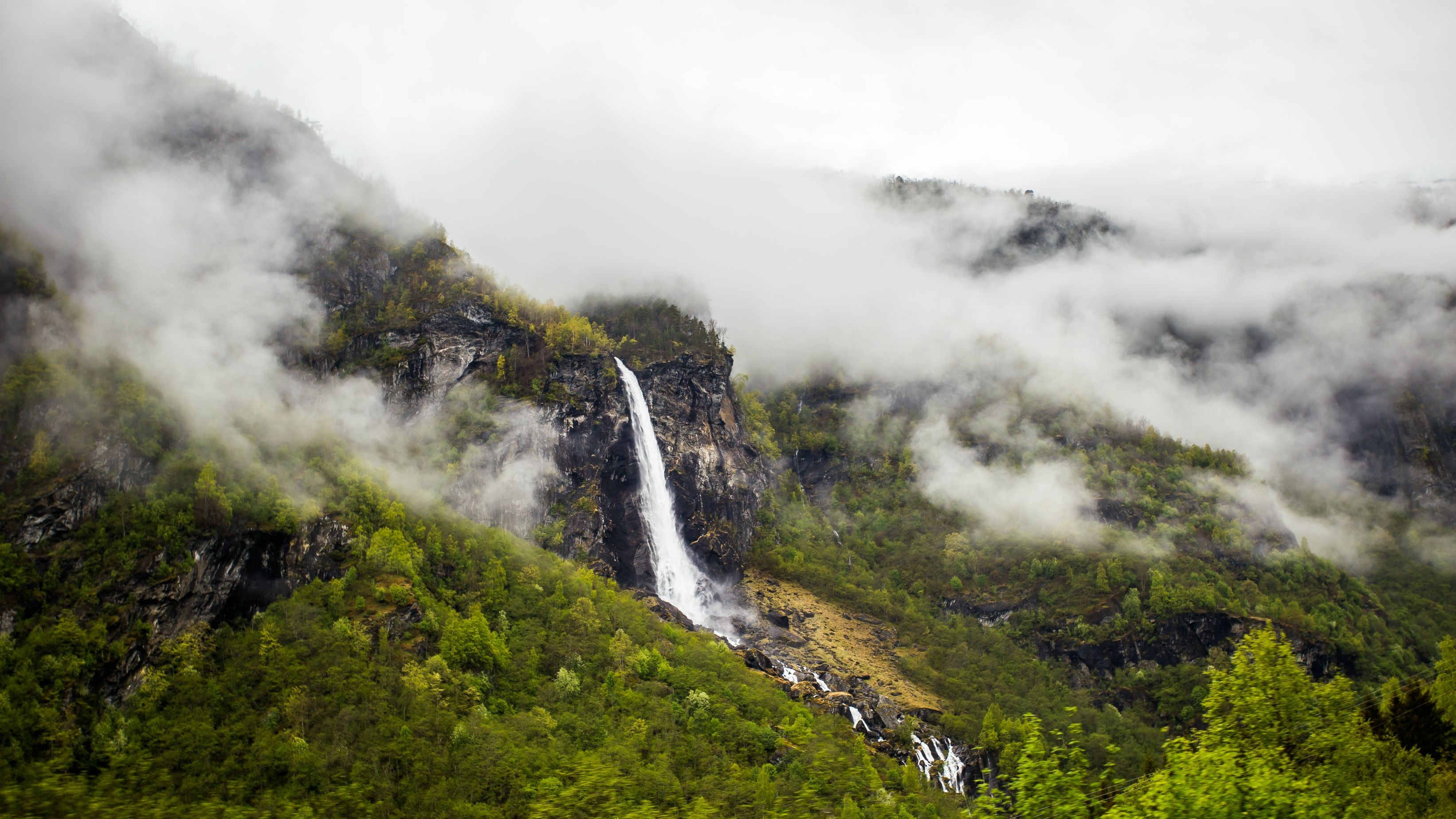 Waterfall cascading down a misty mountain landscape HD Wallpaper