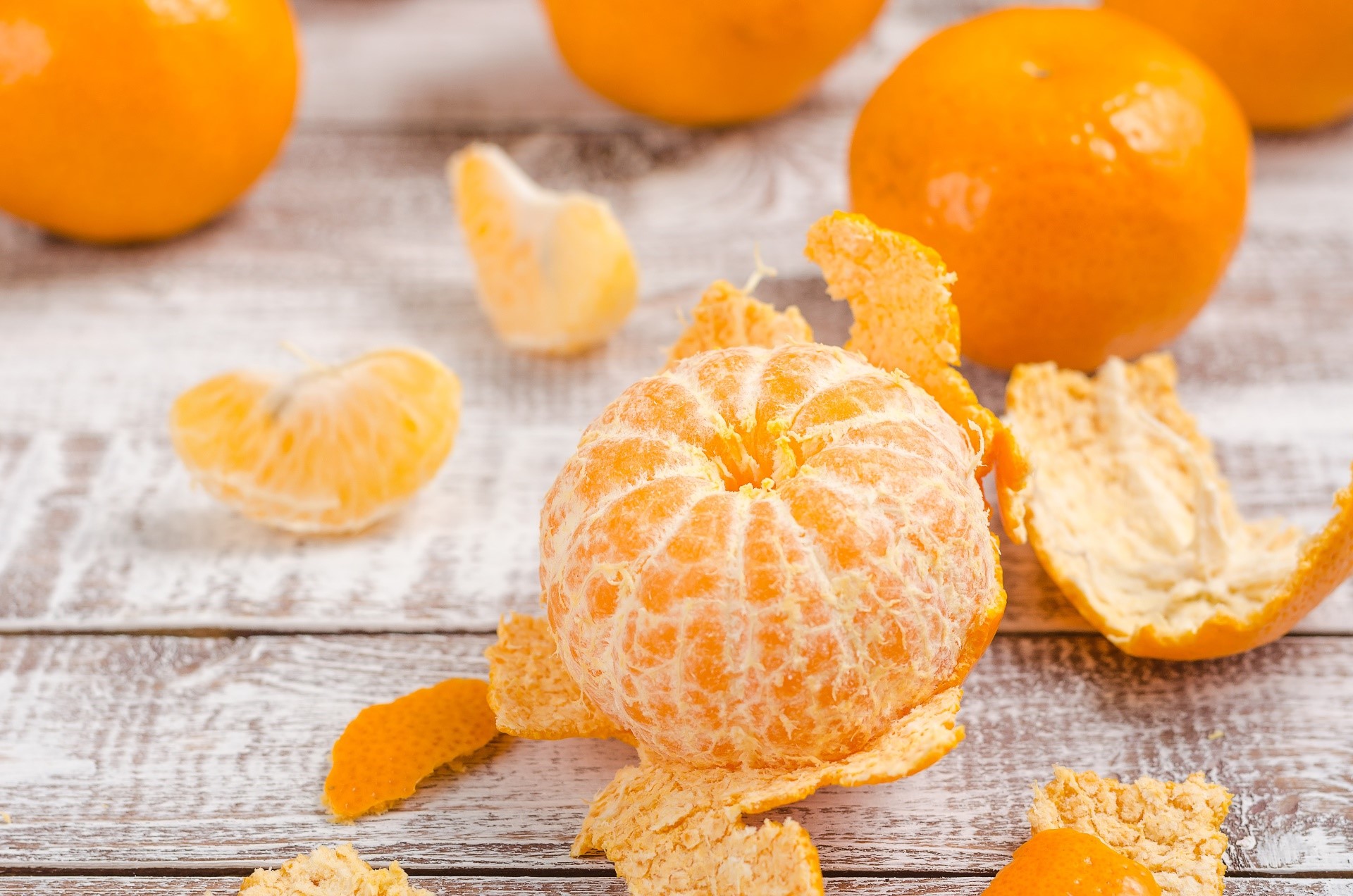 Peeled tangerines and peels on a wooden table HD Wallpaper