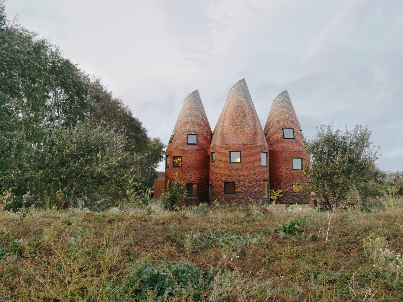 Unusual conical brick houses in a field HD Wallpaper
