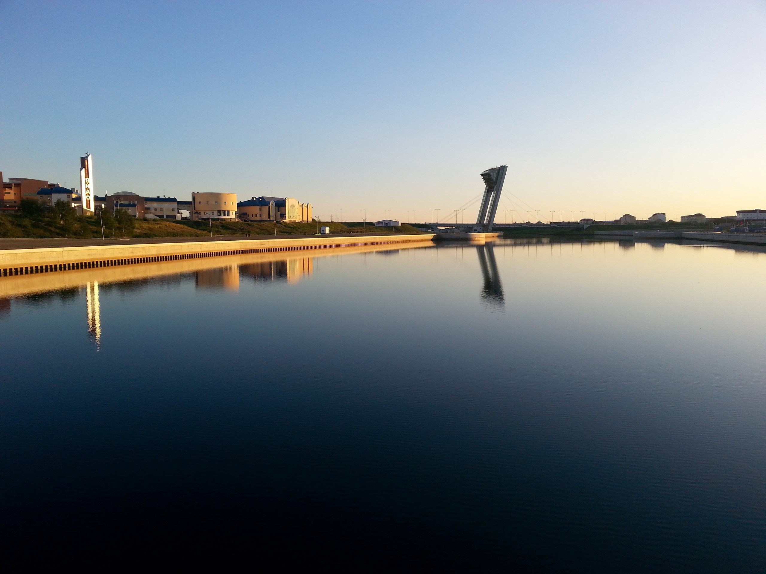 Modern architecture and bridge reflected in calm water at sunrise HD Wallpaper