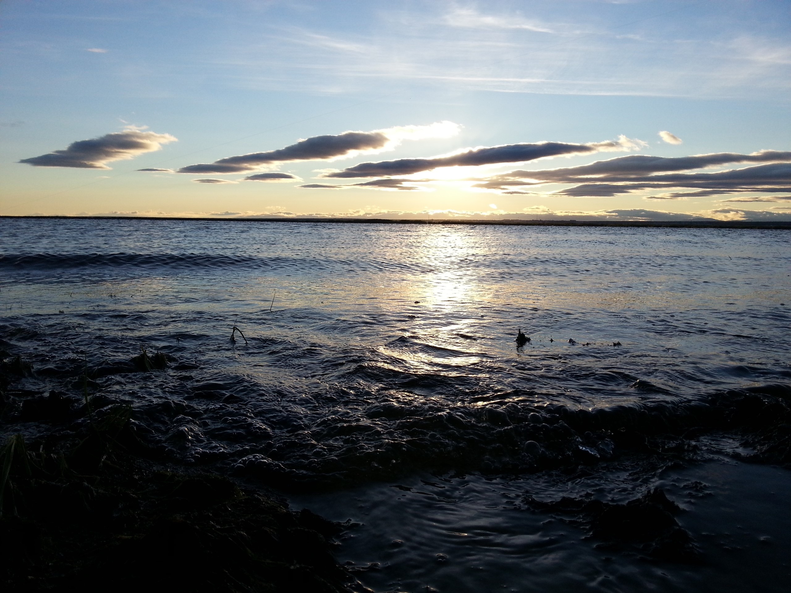Sunset over a calm body of water with clouds HD Wallpaper