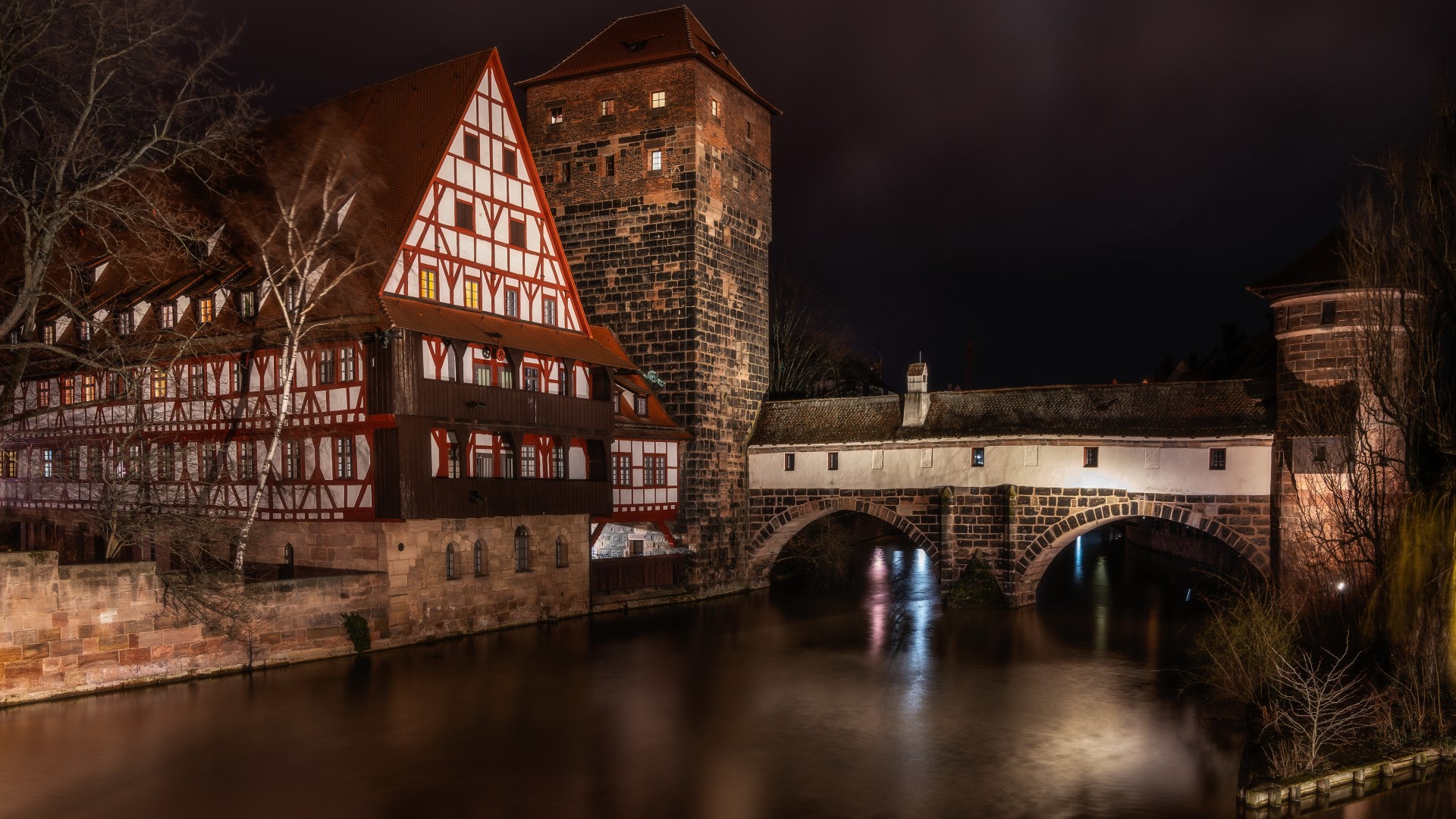 Half-timbered building and bridge over river at night in Nuremberg HD Wallpaper